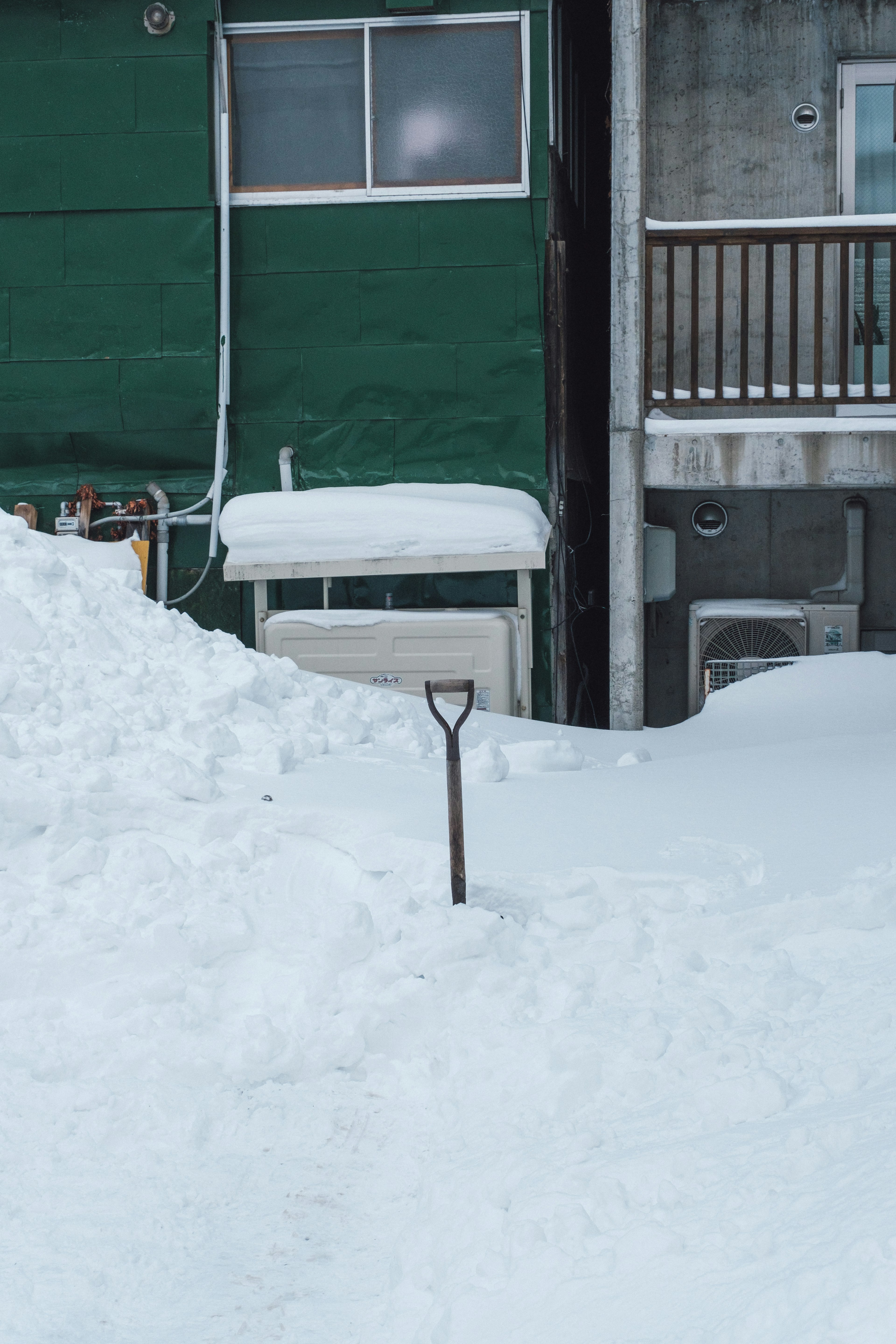 Schneebedeckter Garten mit einem grünen Außengebäude