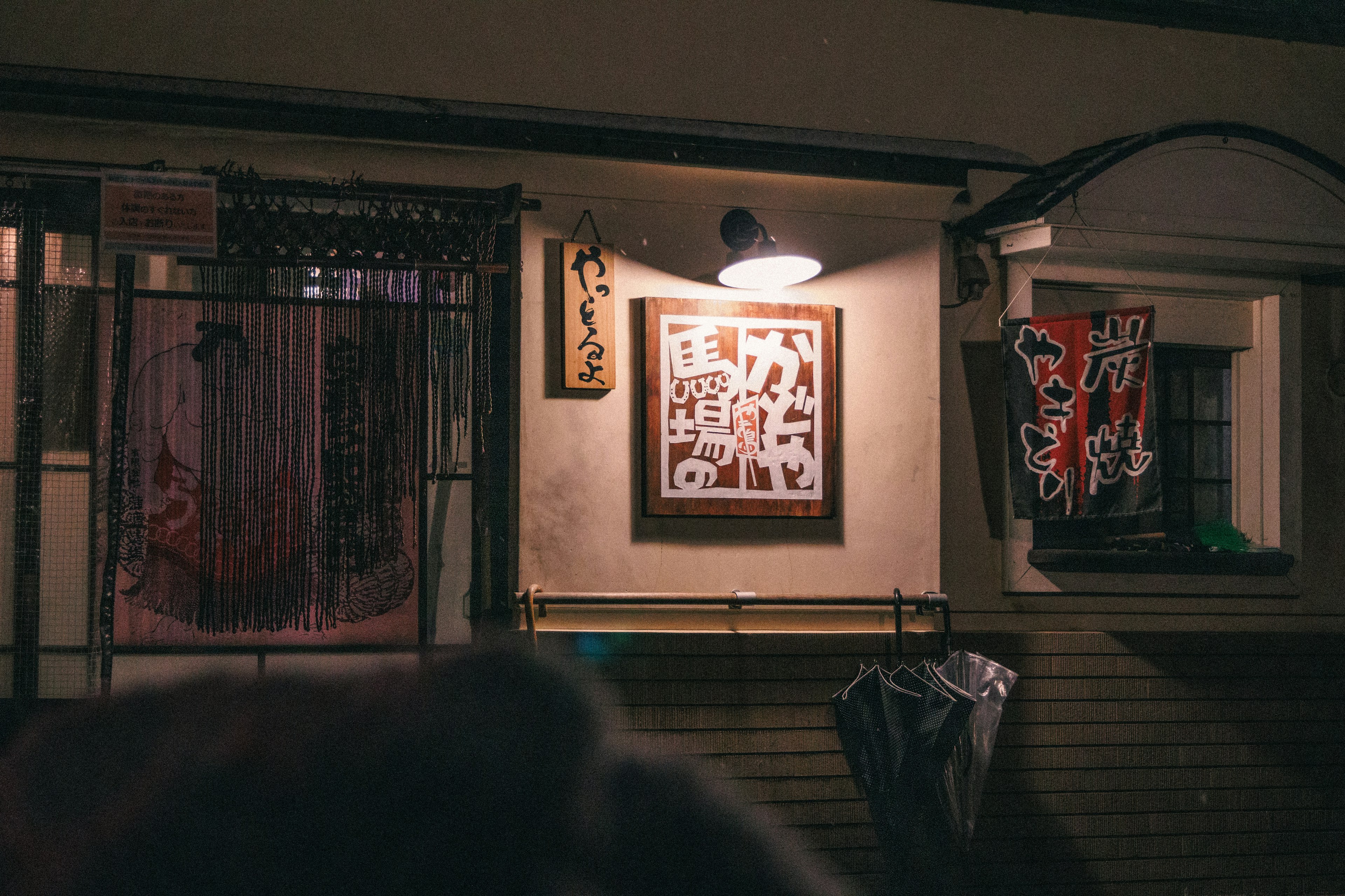 Extérieur d'un magasin la nuit avec une œuvre d'art illuminée sur le mur