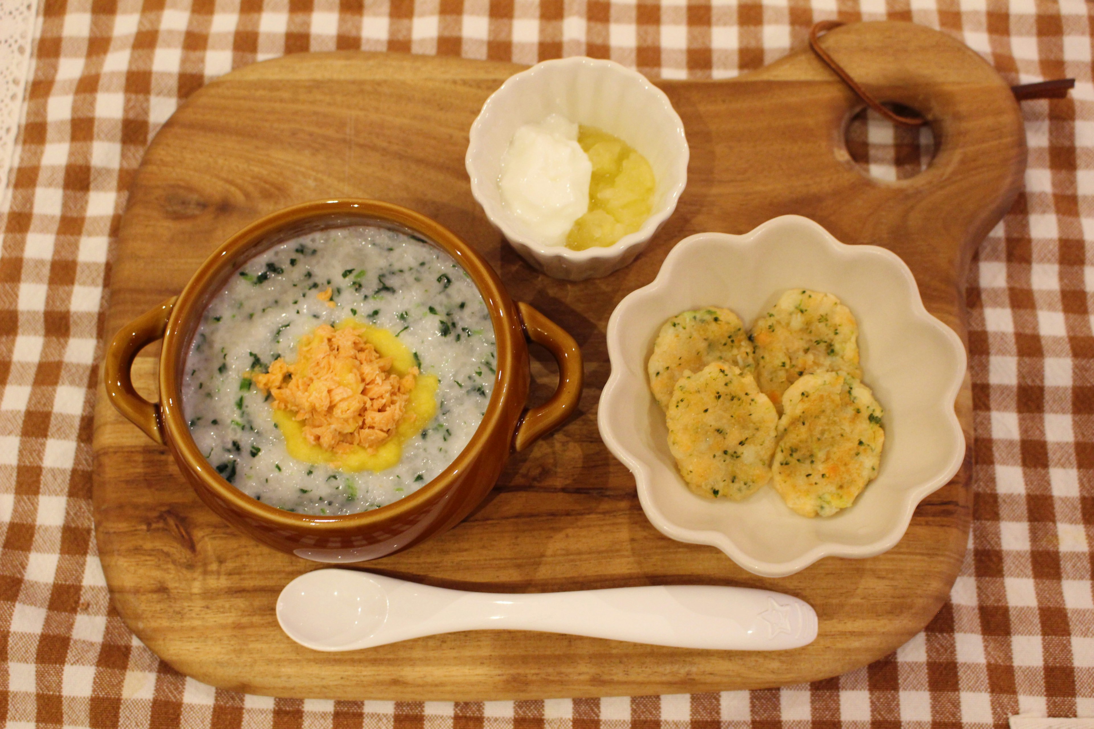 A wooden plate with soup and side dishes served