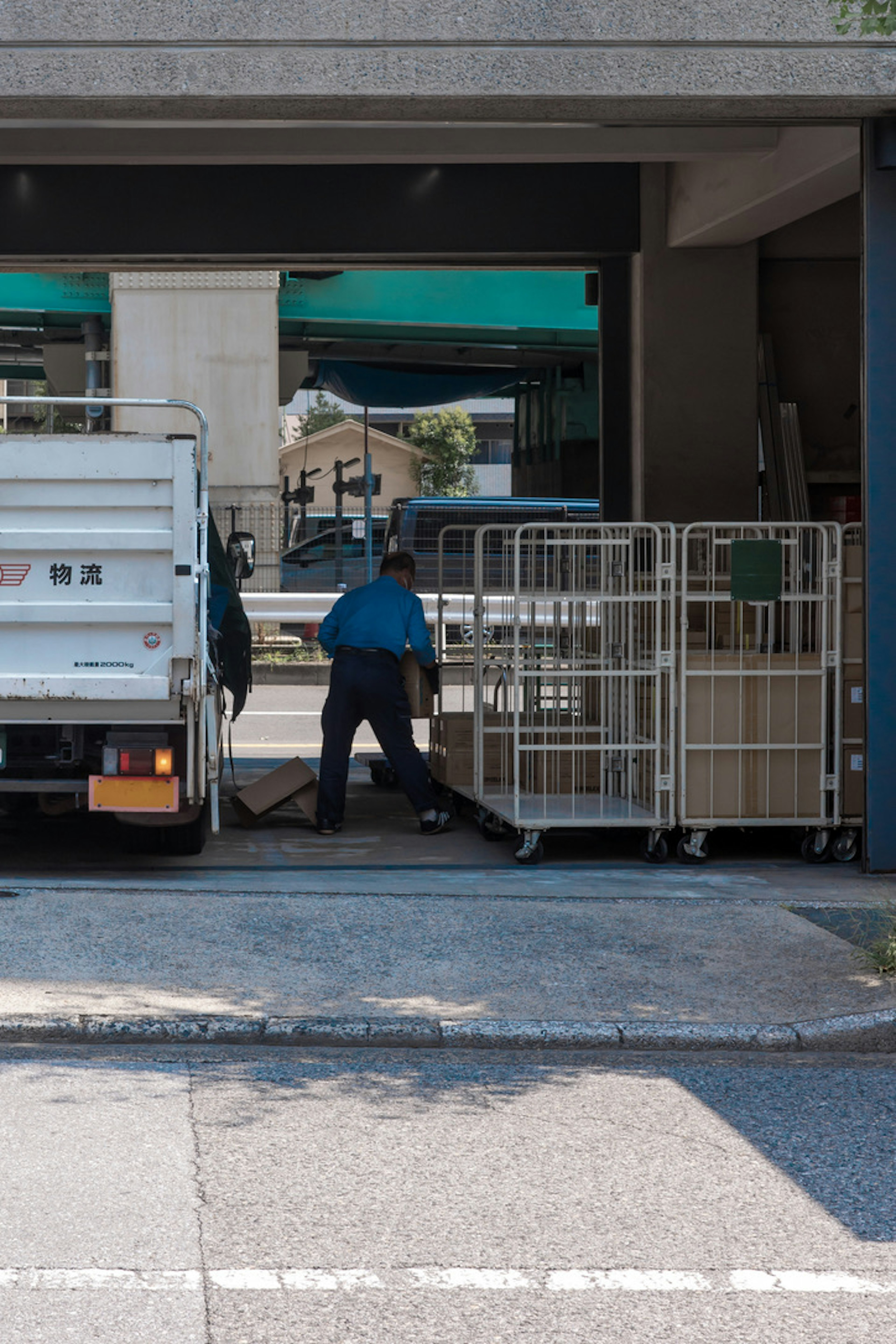 Un lavoratore che scarica articoli da un camion vicino a scaffali metallici in un'area urbana