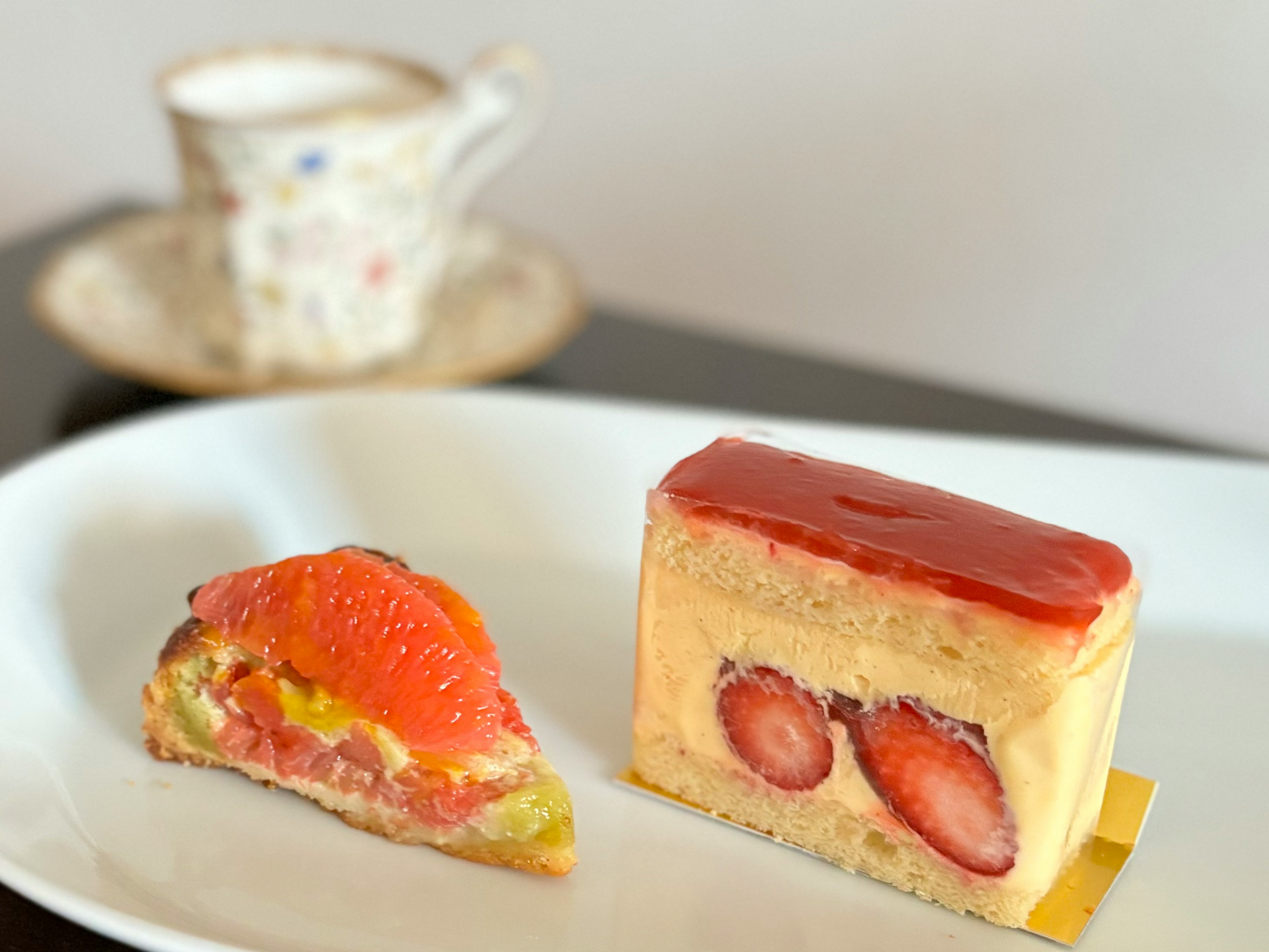 Pastel de fresa y tarta en un plato con una taza de café al fondo