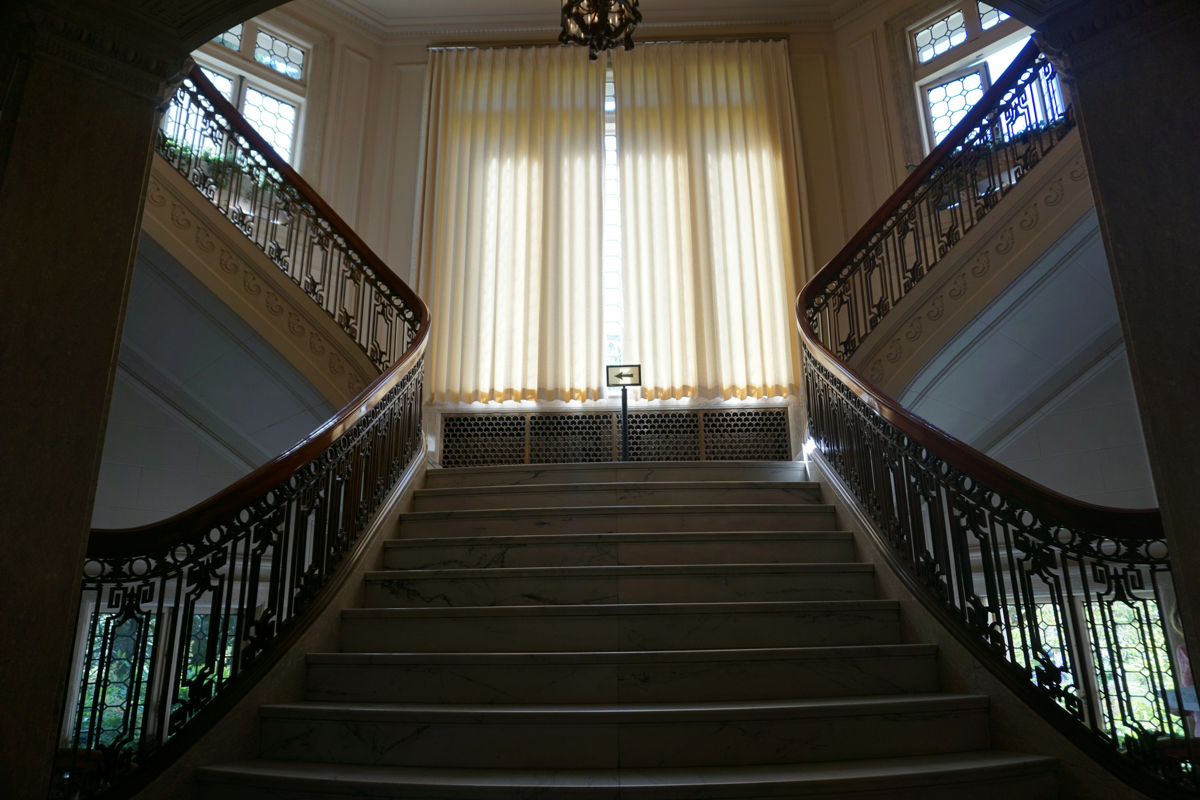 Escalier intérieur élégant avec des rampes décoratives et de la lumière naturelle passant par les fenêtres