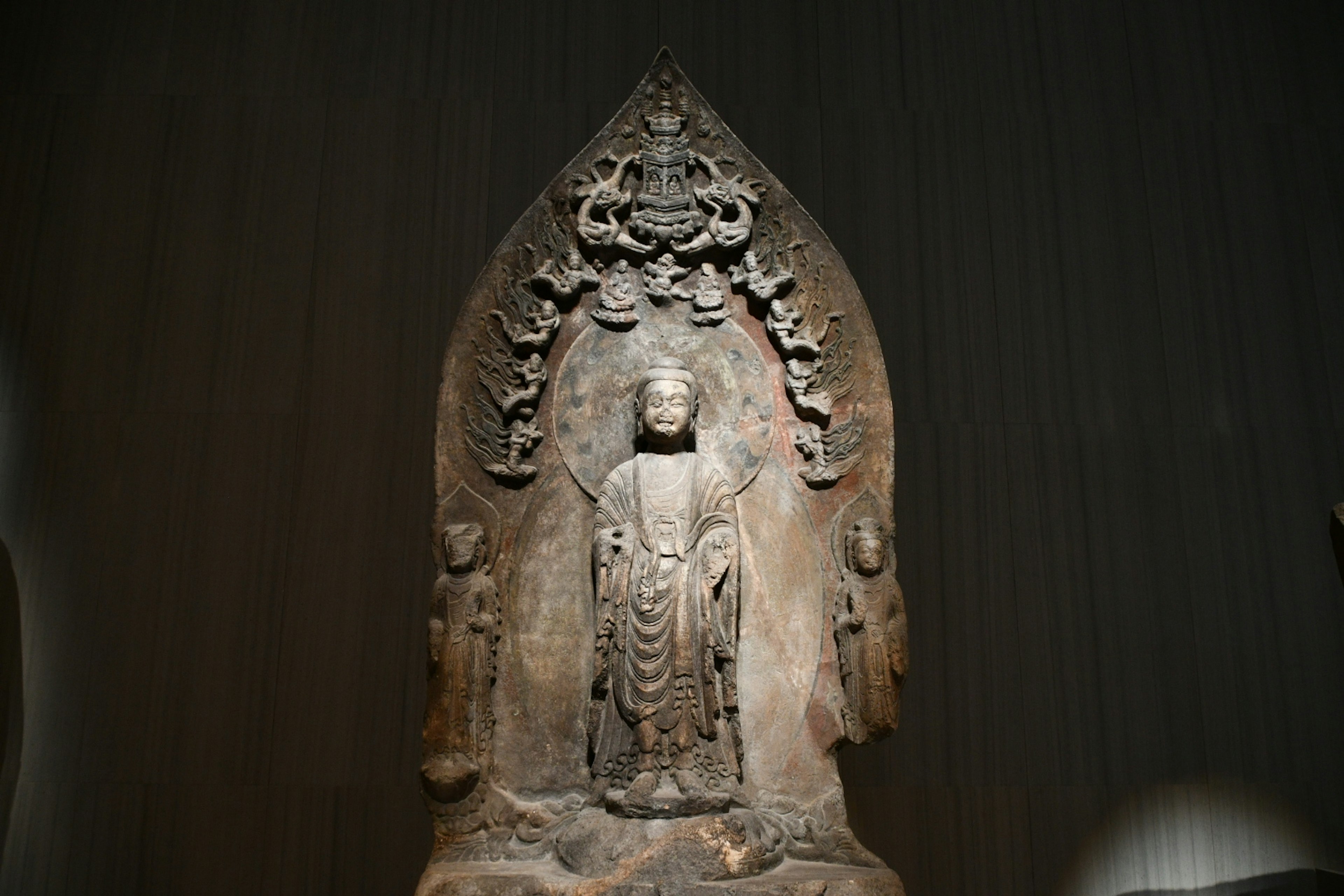 Stone sculpture of a Buddha figure with intricate carvings and decorative elements