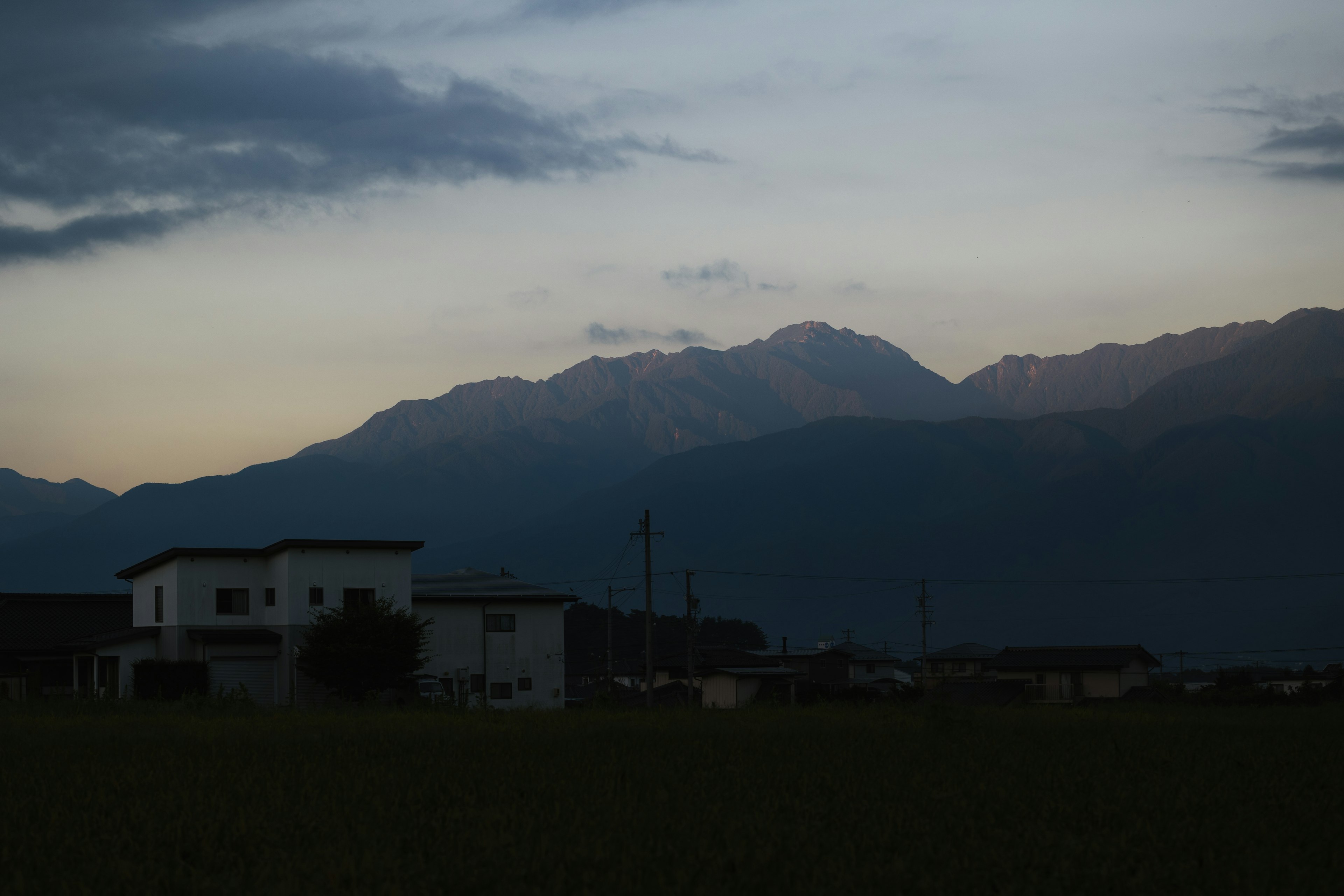 山々が背景に広がる静かな夕暮れの田舎風景