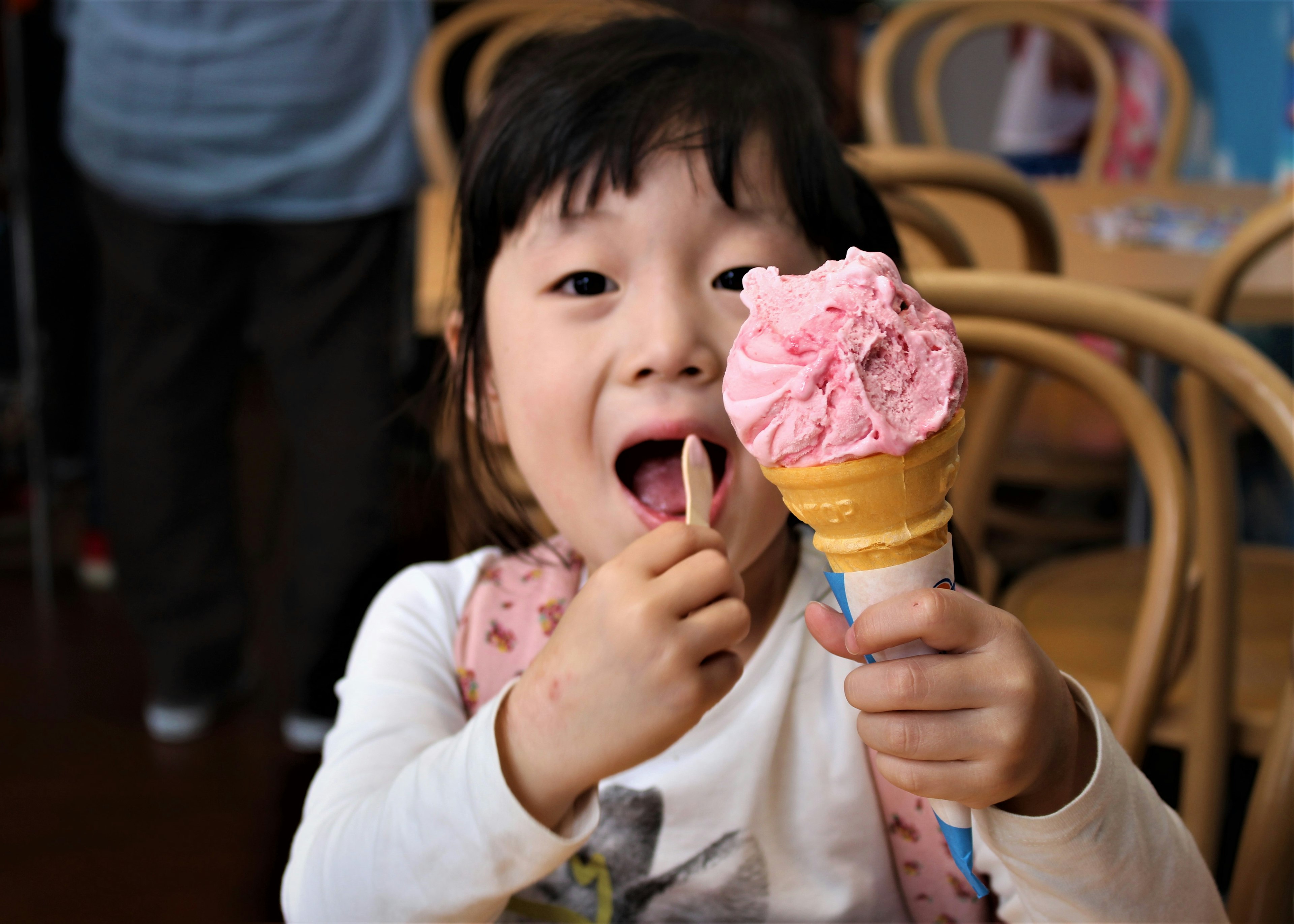 Enfant souriant tenant un cornet de glace rose