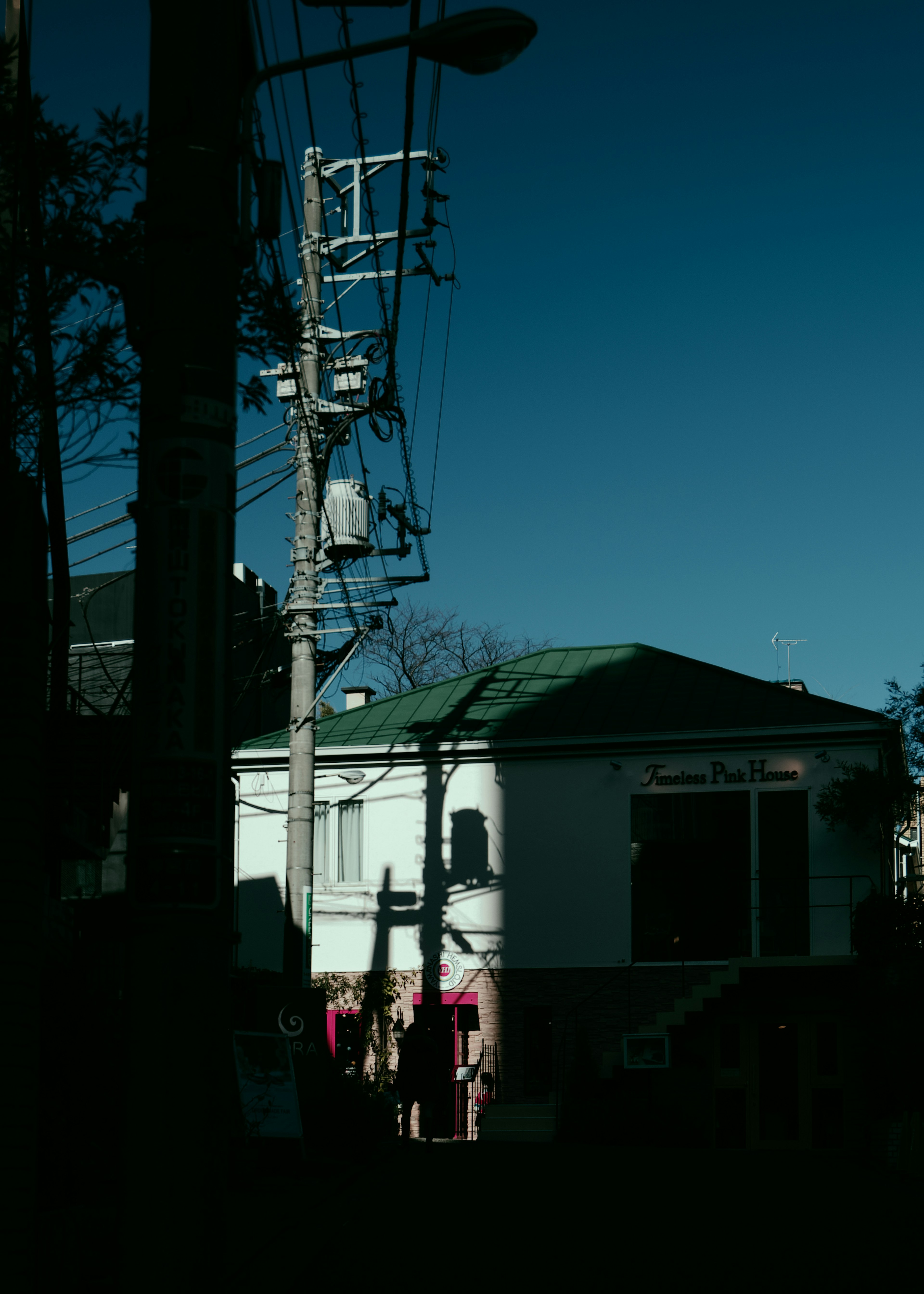 Silhouette of a white house and utility poles under a blue sky