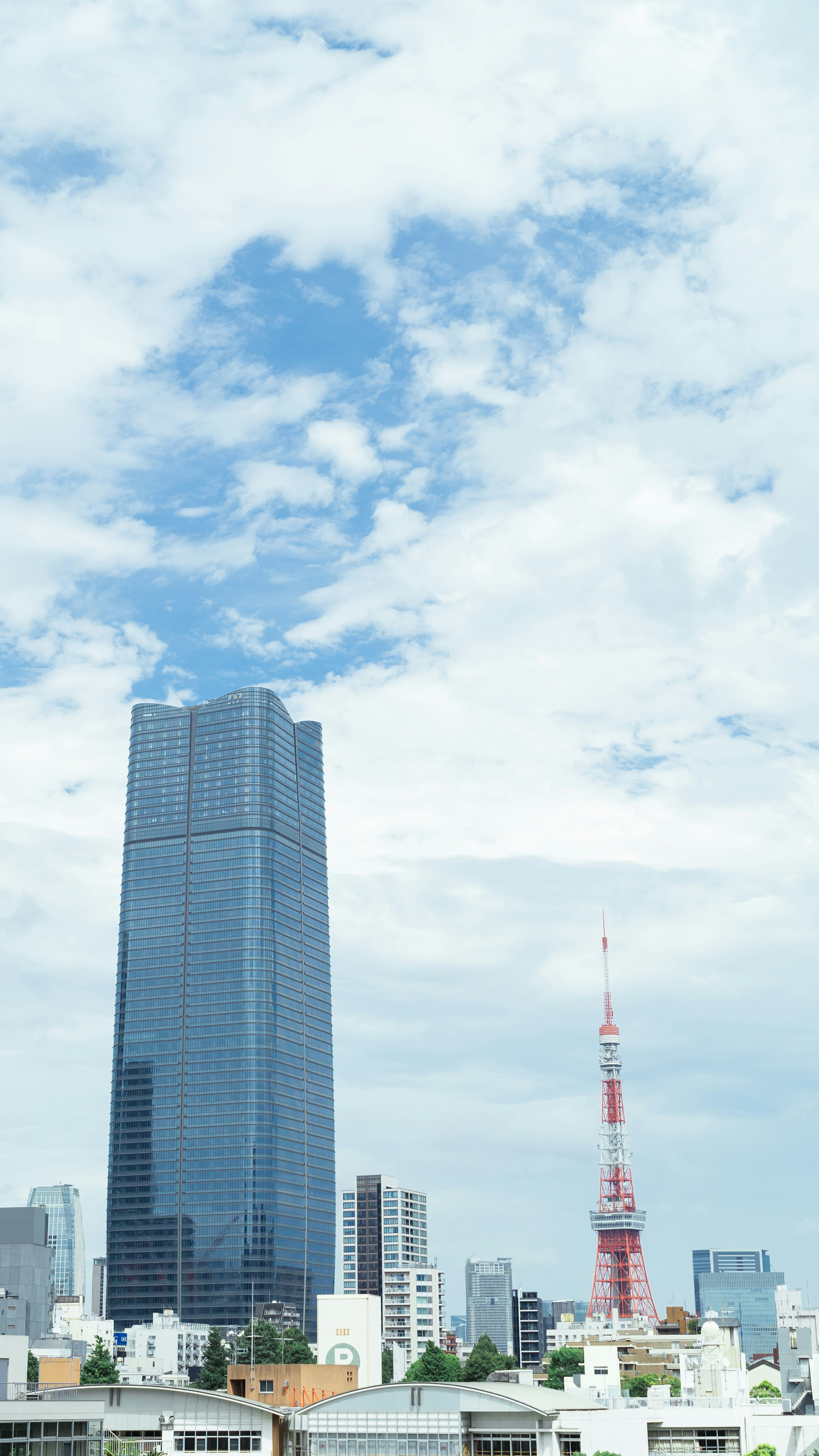 Stadtansicht mit einem hohen Wolkenkratzer und dem Tokyo Tower unter einem blauen Himmel