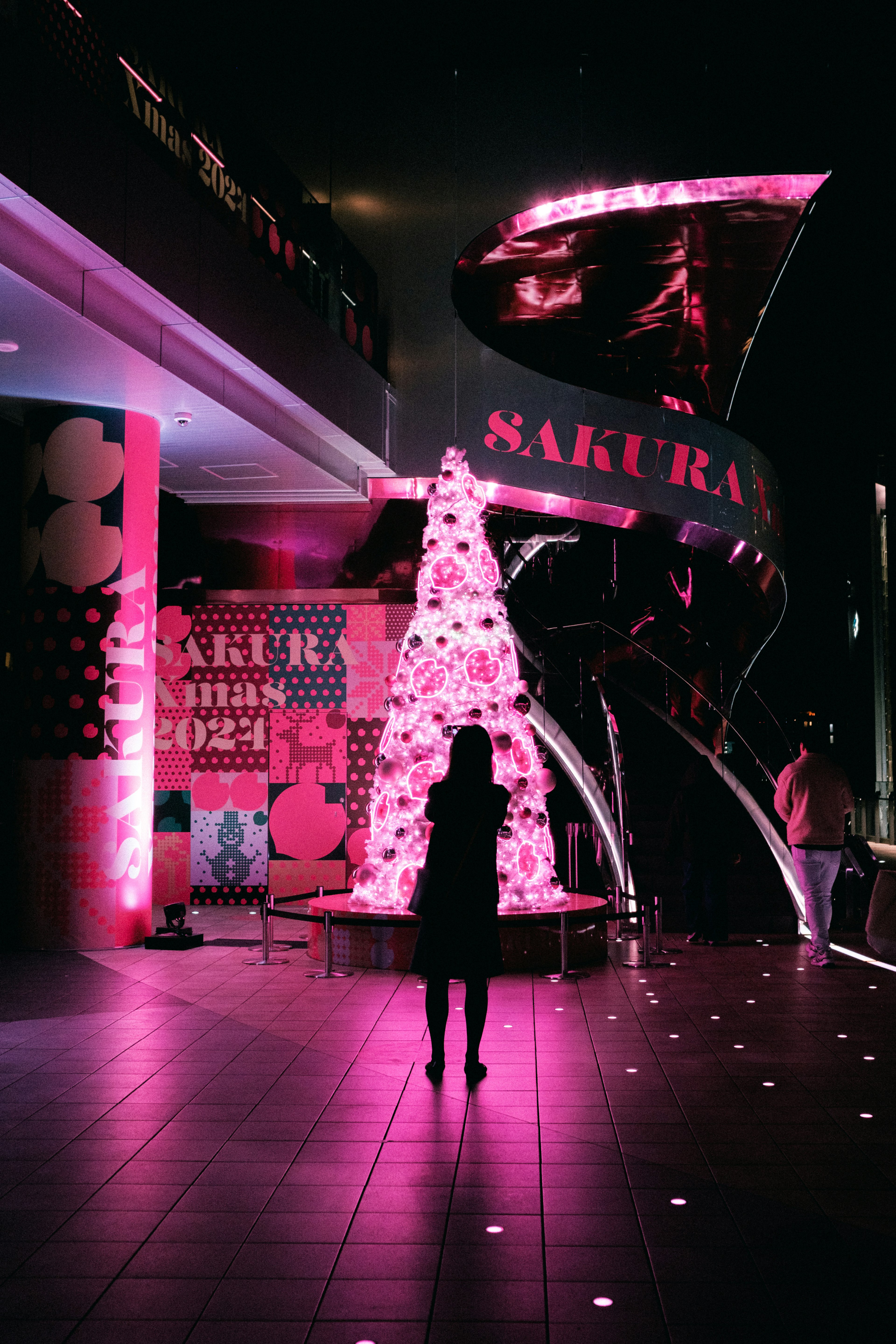 Silhouette of a person in front of a pink Sakura-themed decoration with artistic background