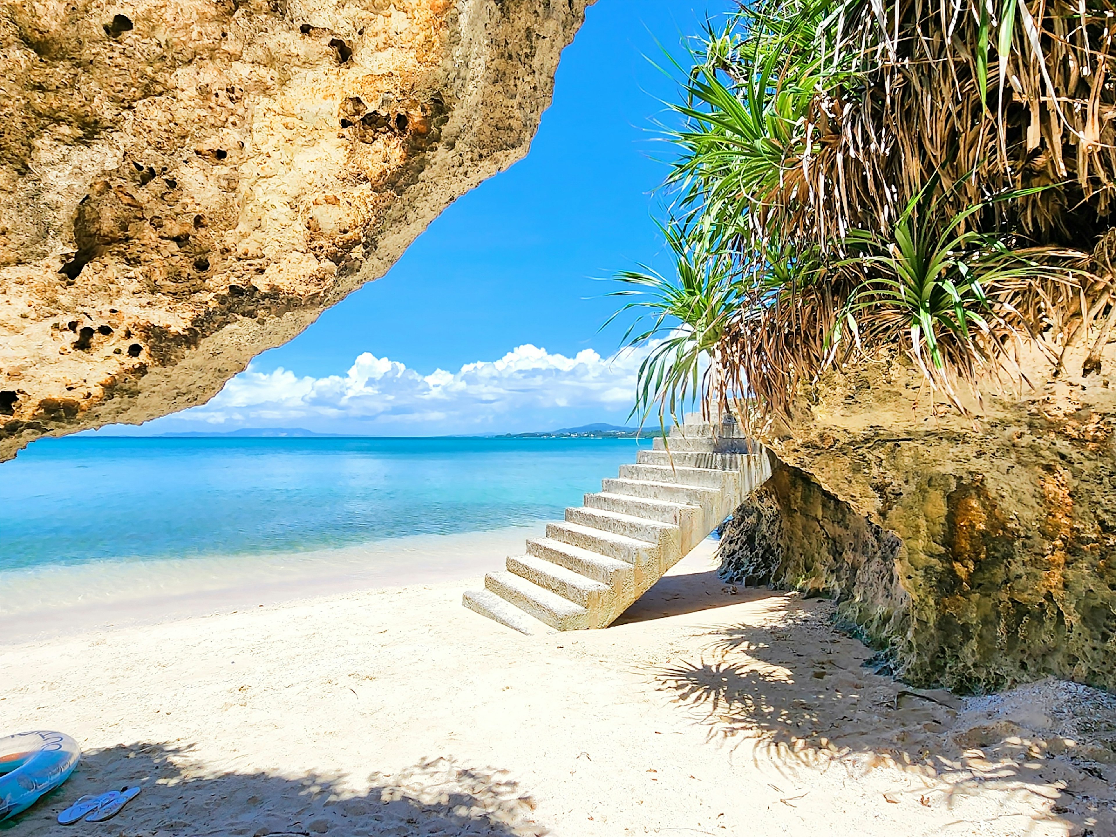 Escena de playa con escaleras que conducen al agua rodeada de océano azul y arena blanca