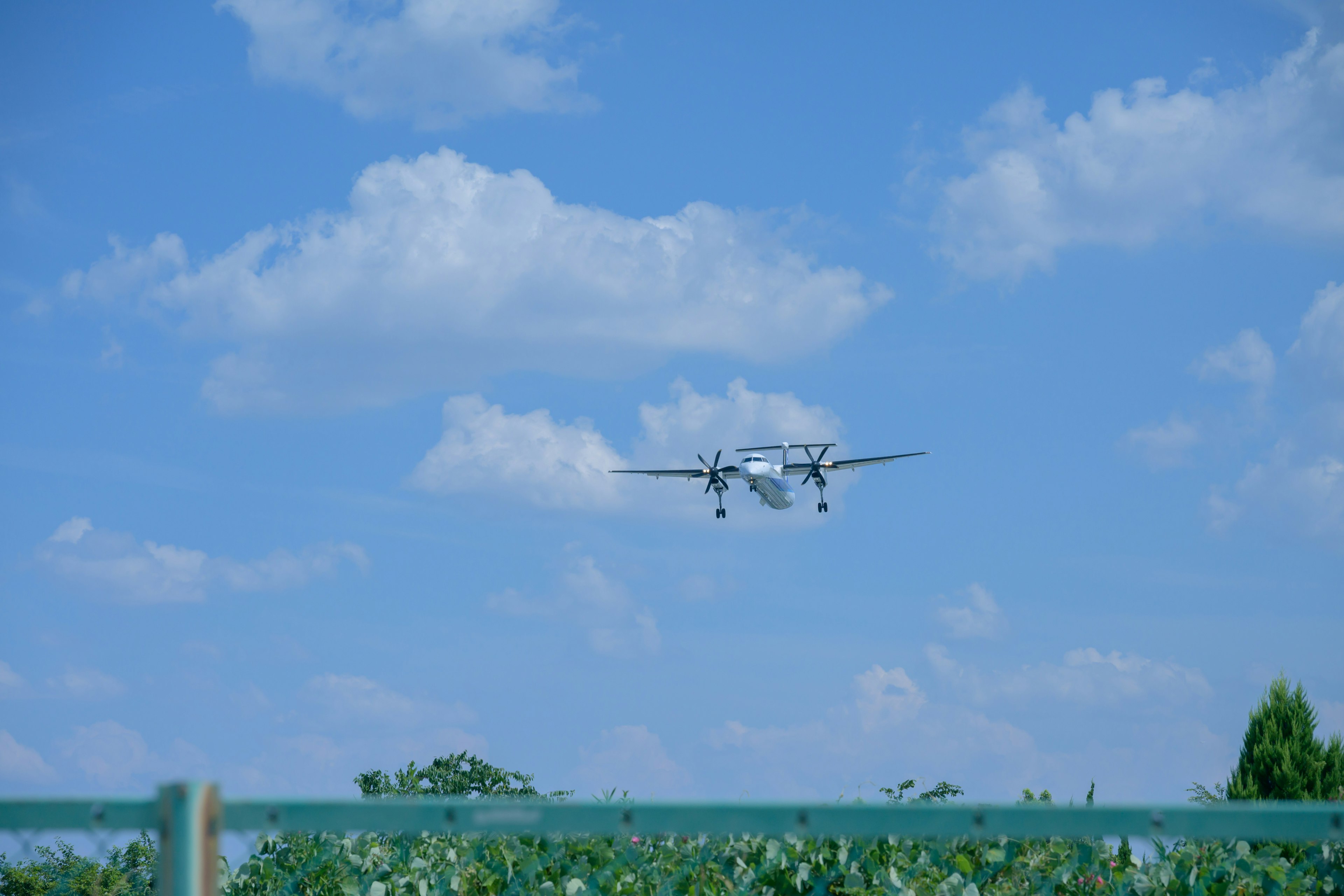 An airplane landing under a blue sky with fluffy clouds