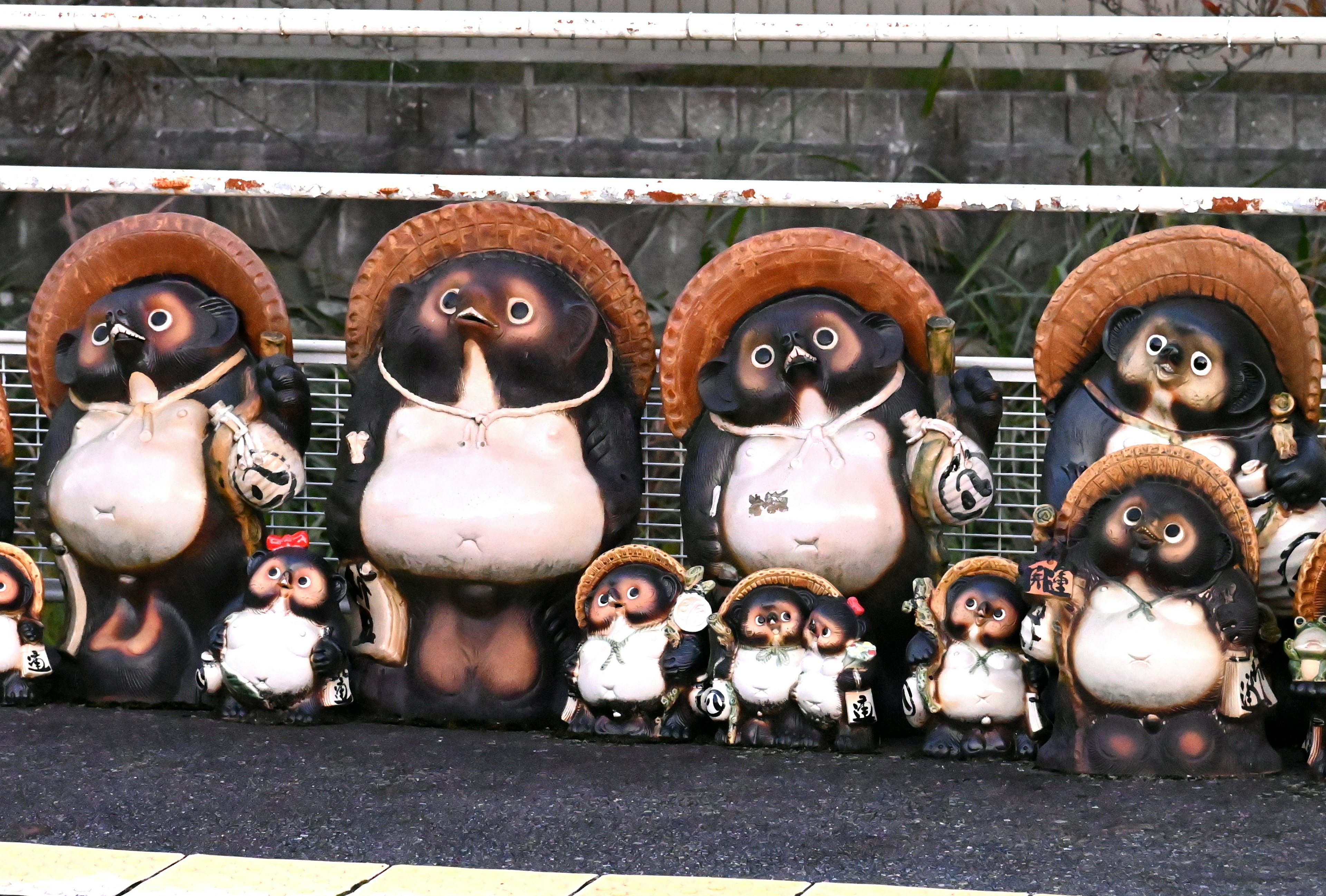 A row of ceramic tanuki figurines with straw hats