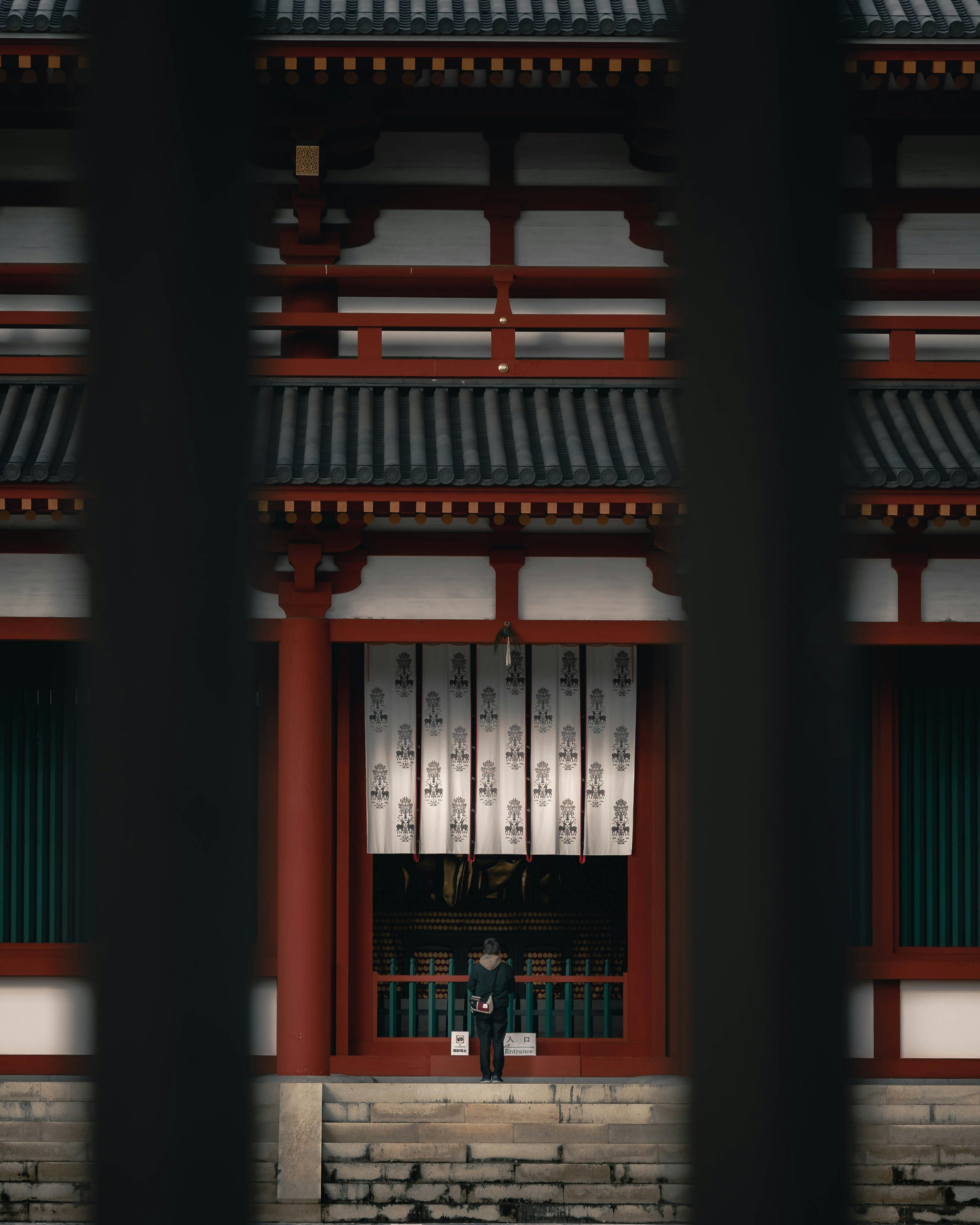 Extérieur d'un temple japonais traditionnel avec une personne devant un bâtiment rouge