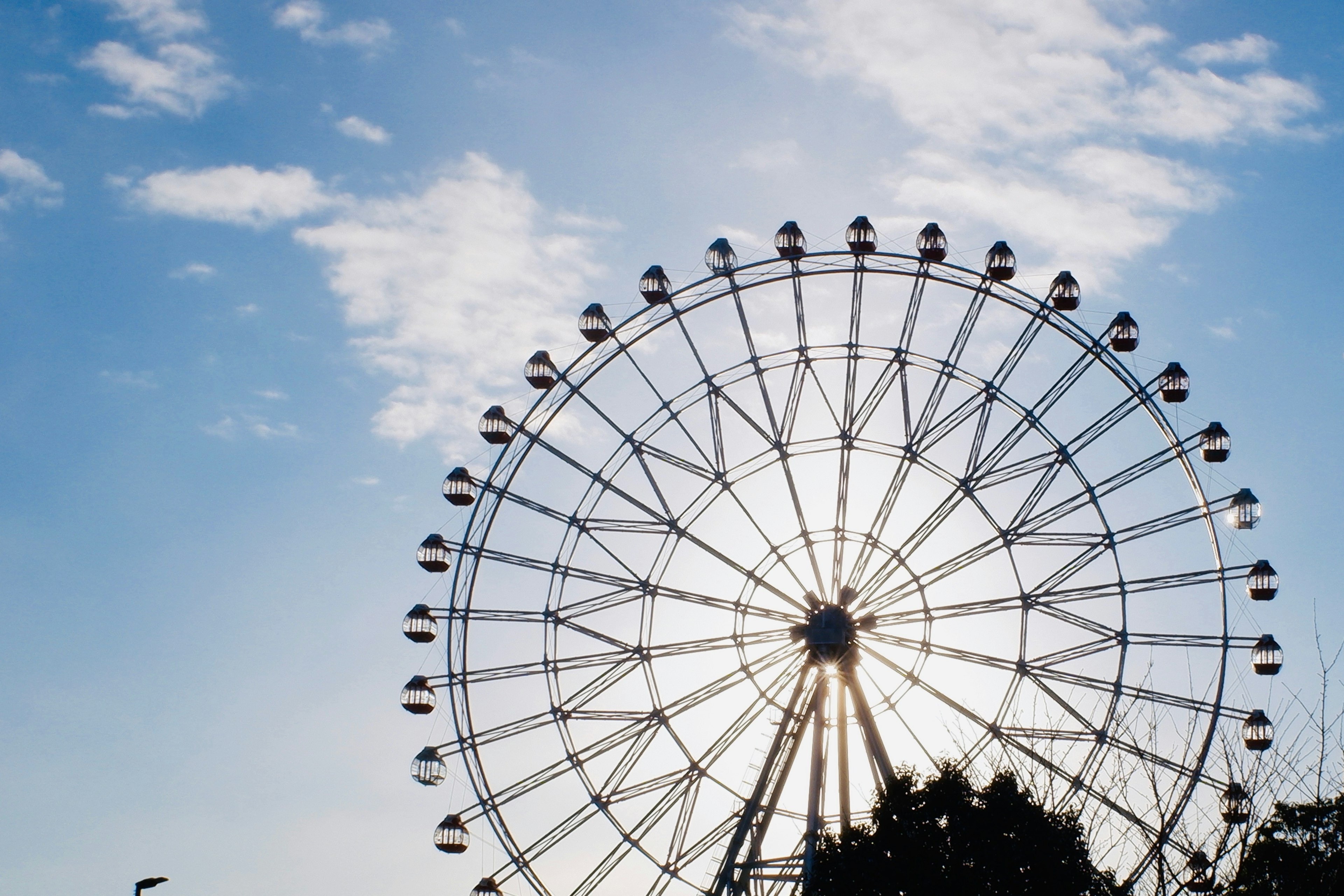 Silhouette of a Ferris wheel against a blue sky