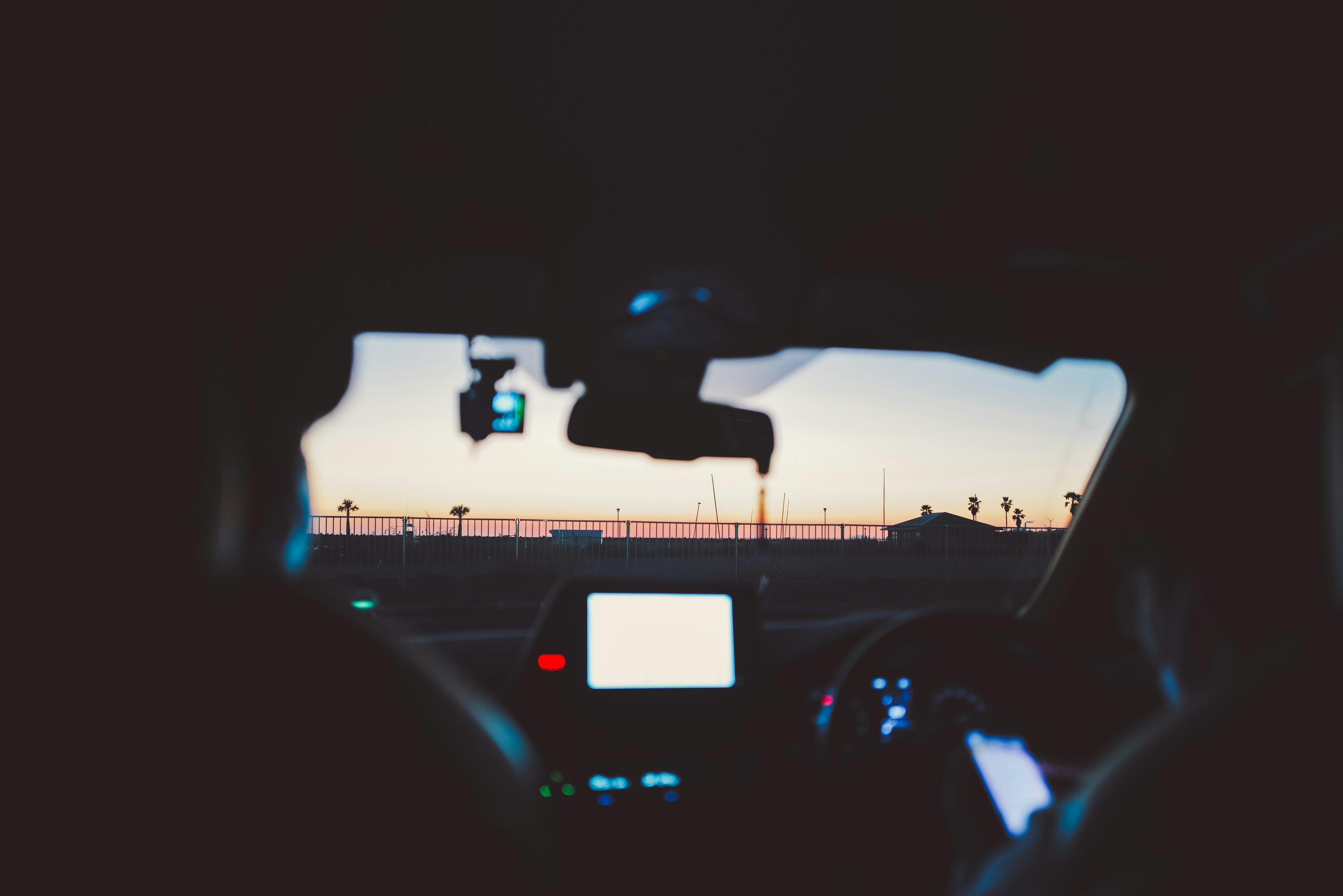 View of sunset from inside a car showing driver and passenger hands