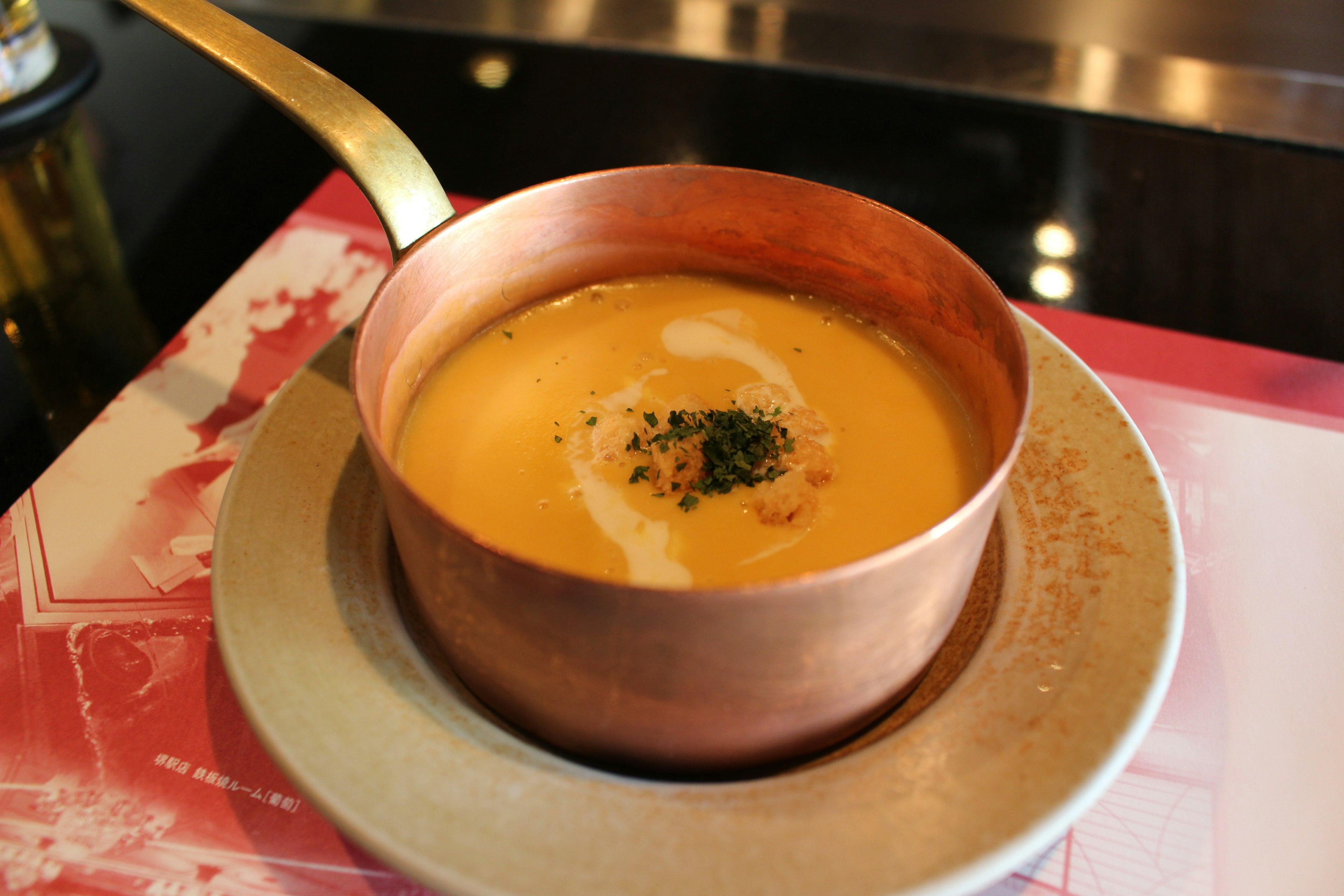 Zuppa cremosa servita in un pentolino di metallo con guarnizione