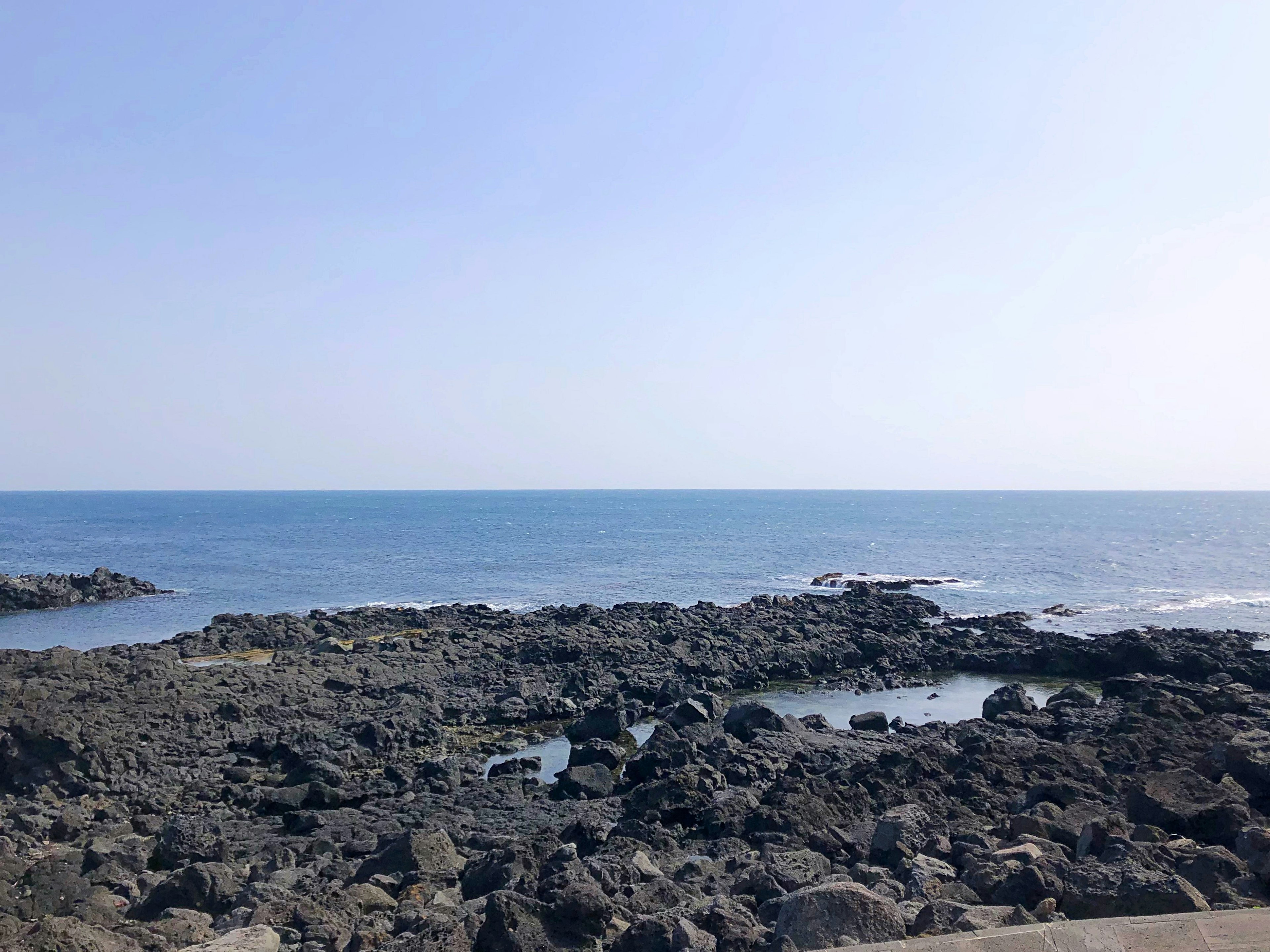 Paesaggio marino con costa rocciosa sotto un cielo blu chiaro