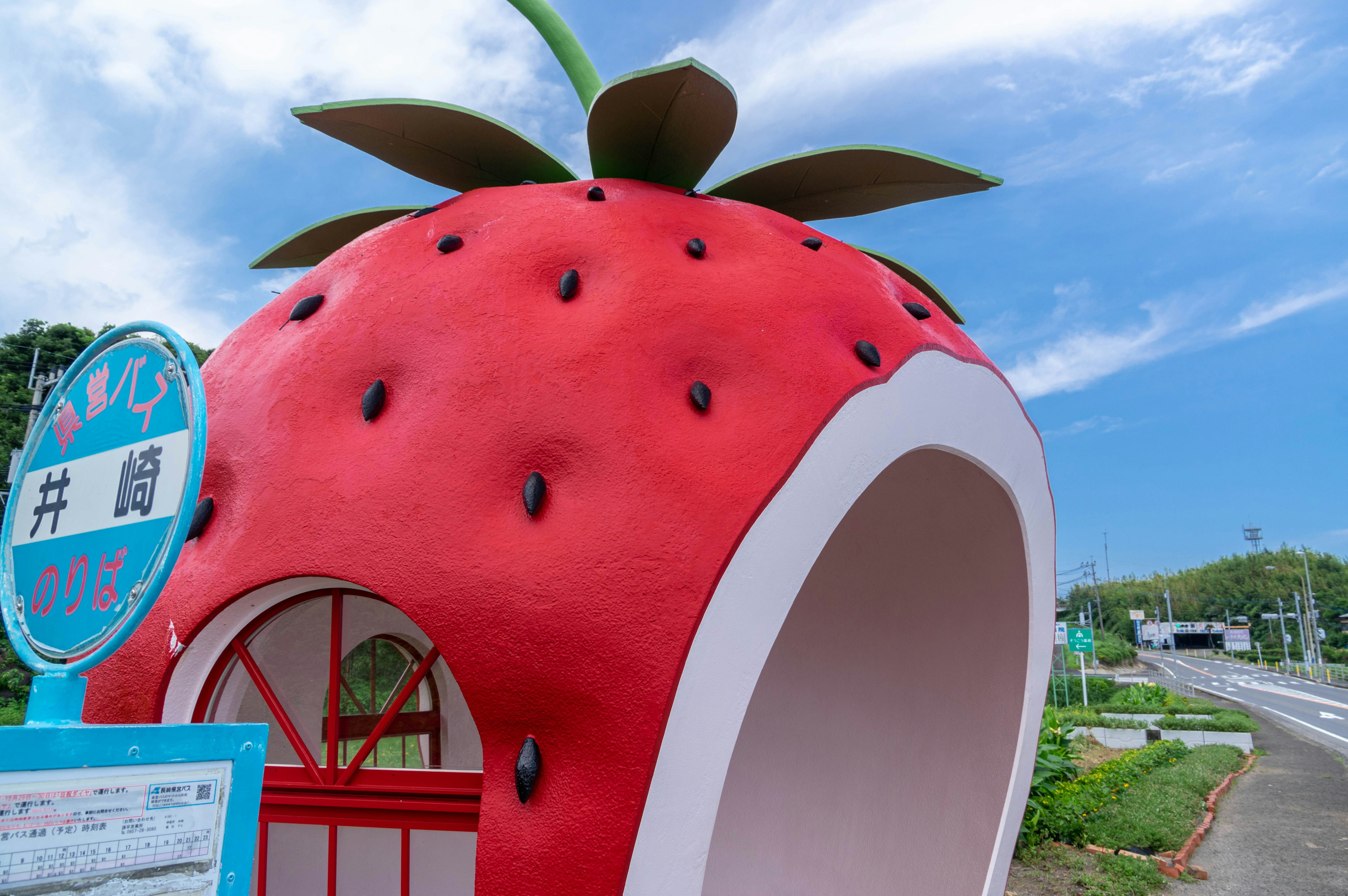 Una fermata dell'autobus a forma di fragola sotto un cielo blu