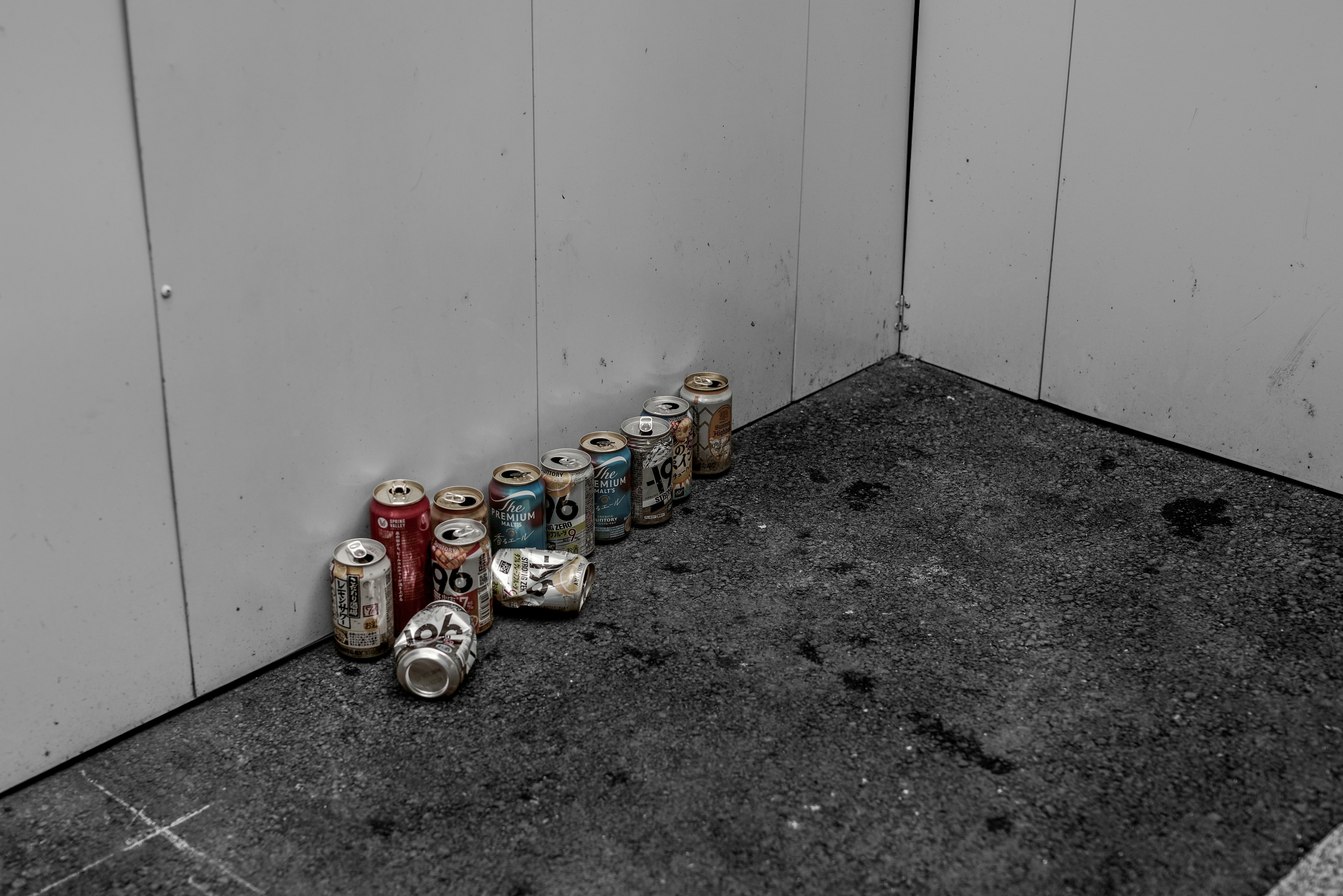 A row of empty cans stacked in a corner against a wall