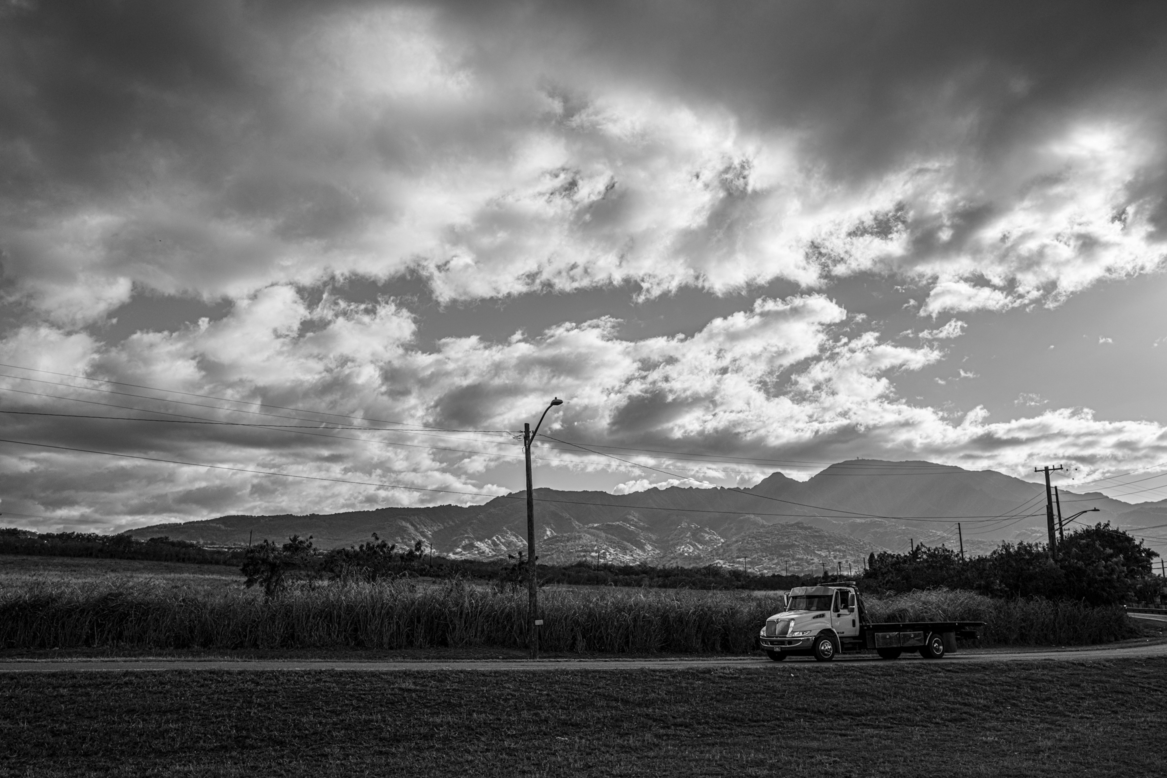 白黒の風景写真にトラックと山々が描かれている