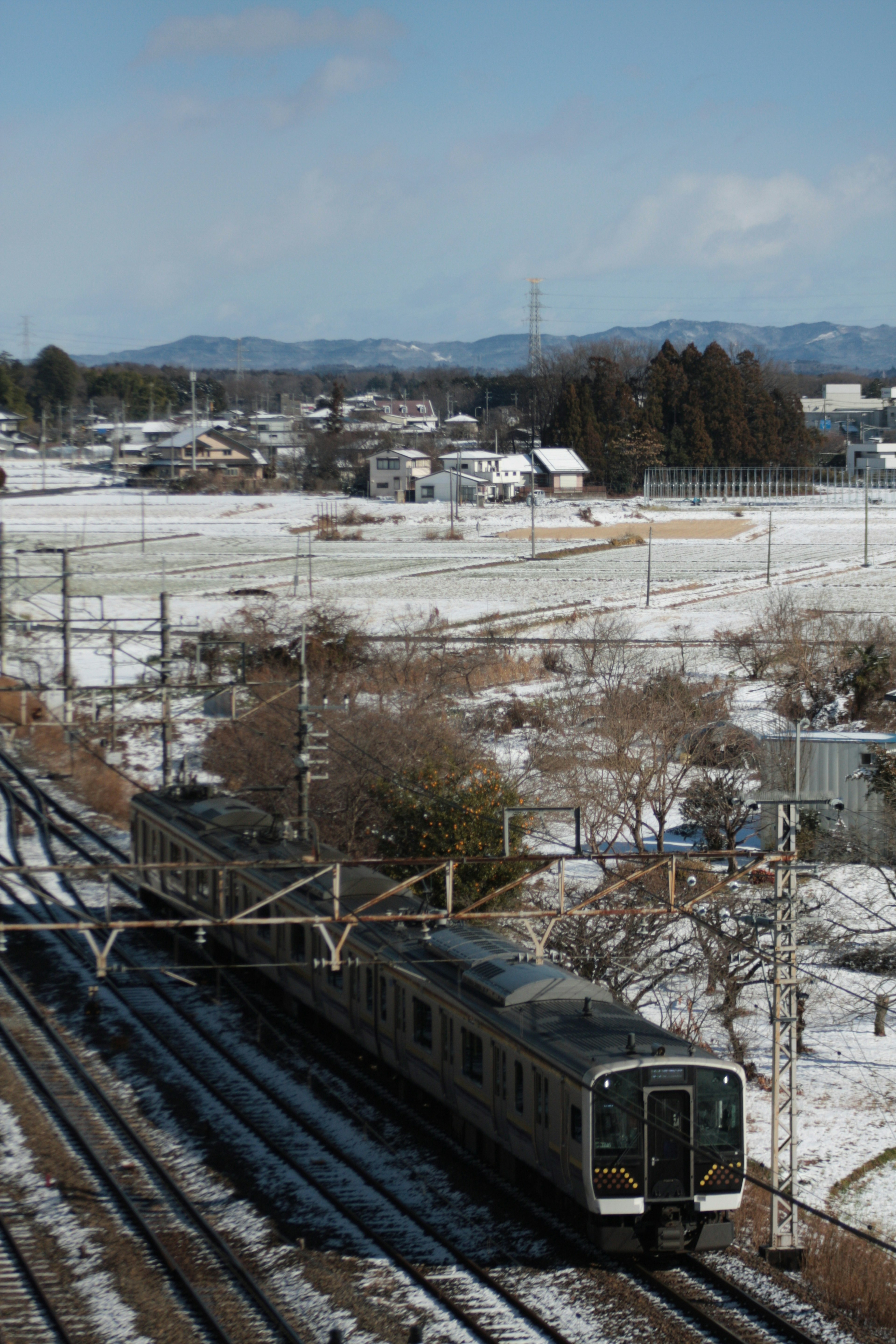 รถไฟที่วิ่งผ่านภูมิทัศน์ที่มีหิมะพร้อมรางรถไฟที่มองเห็นได้