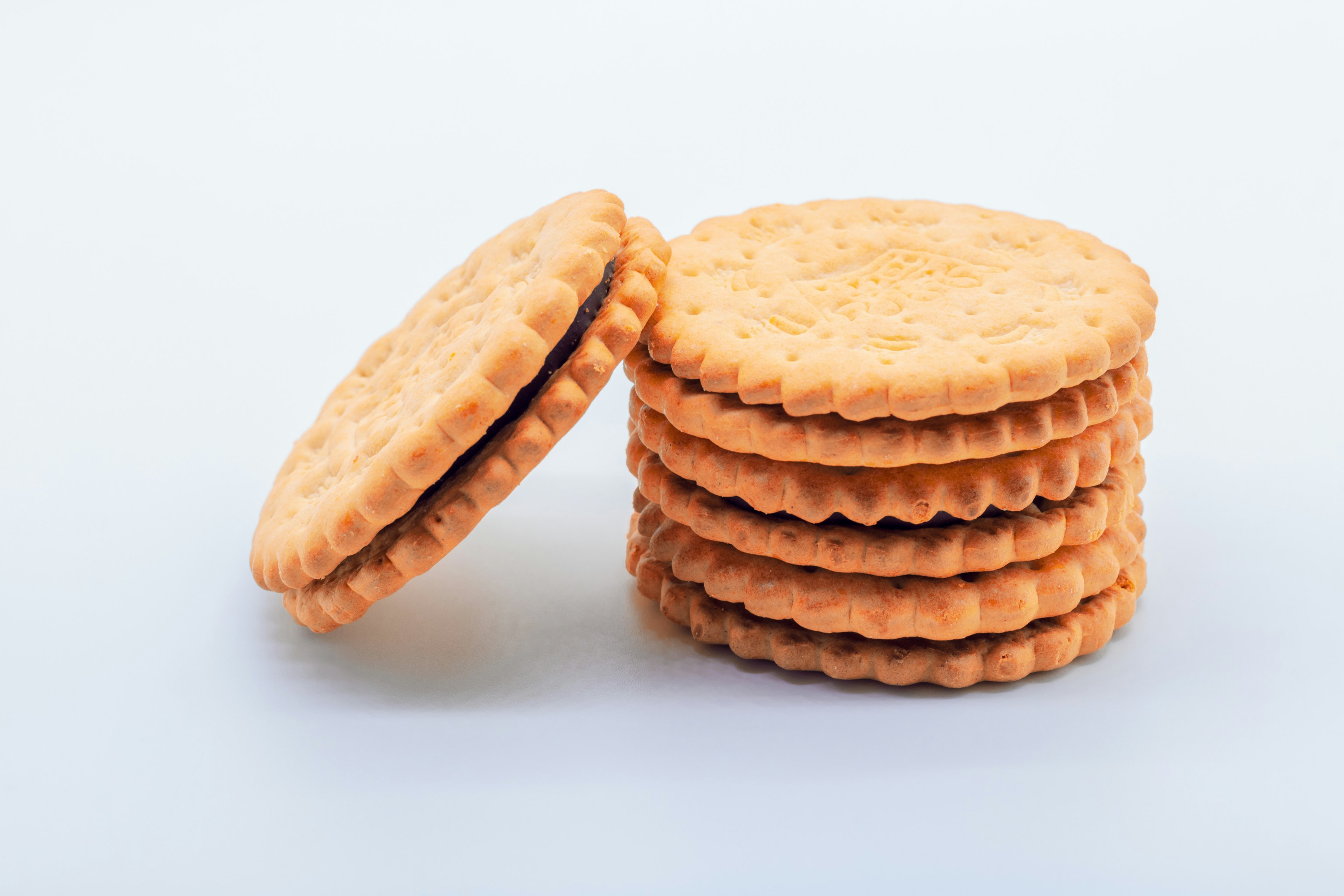 Mucchio di biscotti arancioni ripieni di crema su sfondo bianco