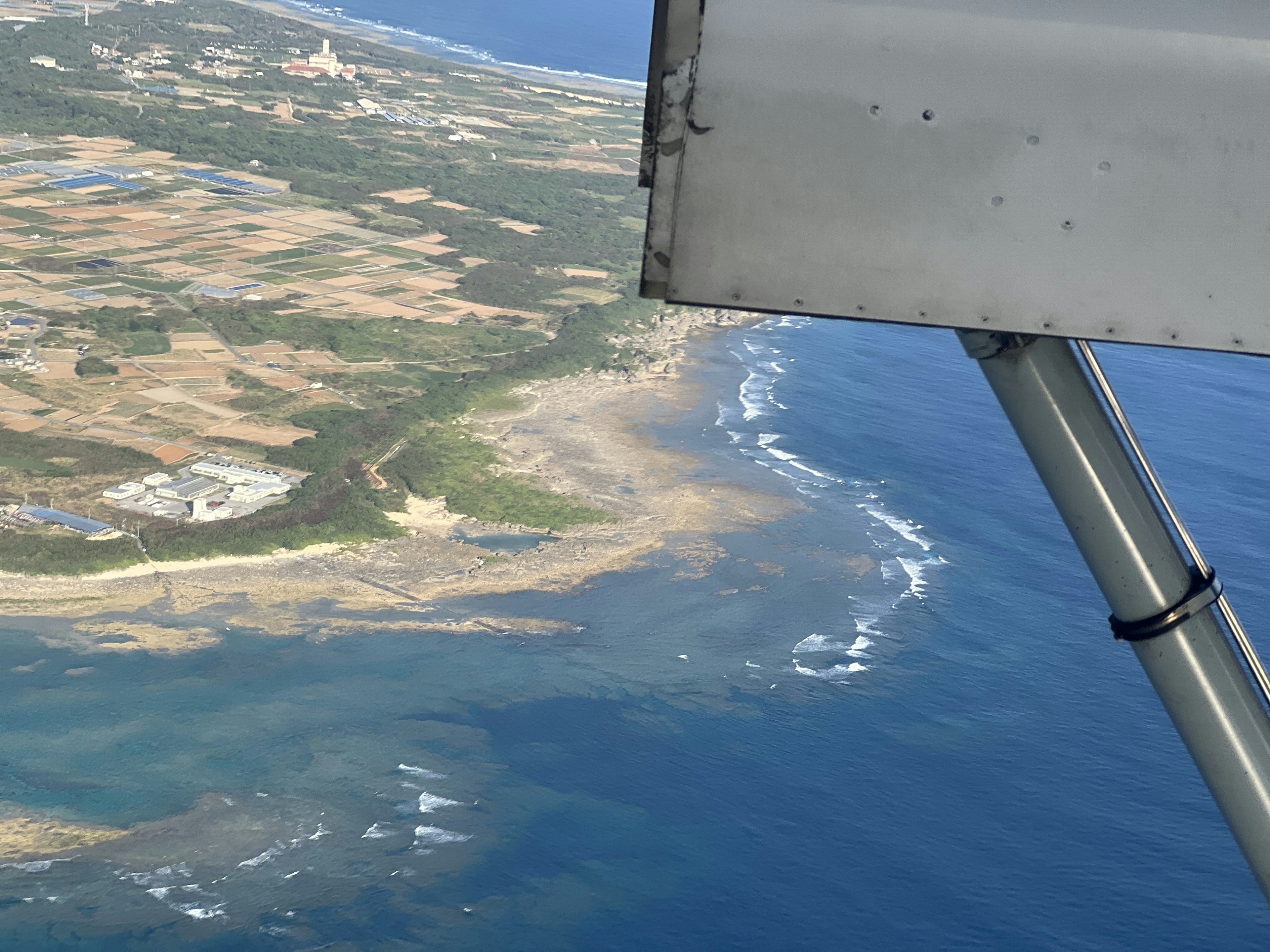 View from an airplane window showing coastline and blue ocean