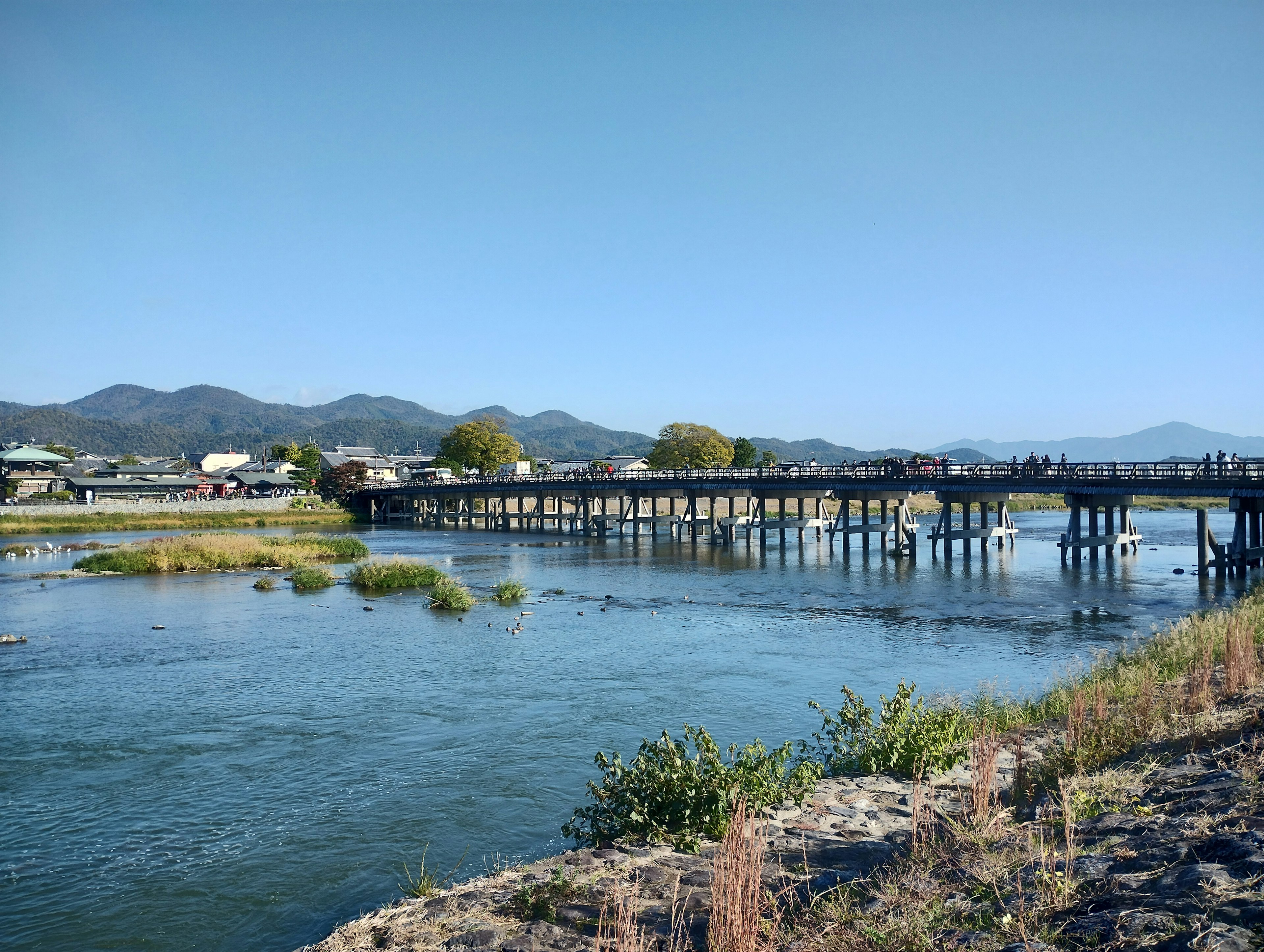 Pemandangan indah sungai dan jembatan kayu di bawah langit biru