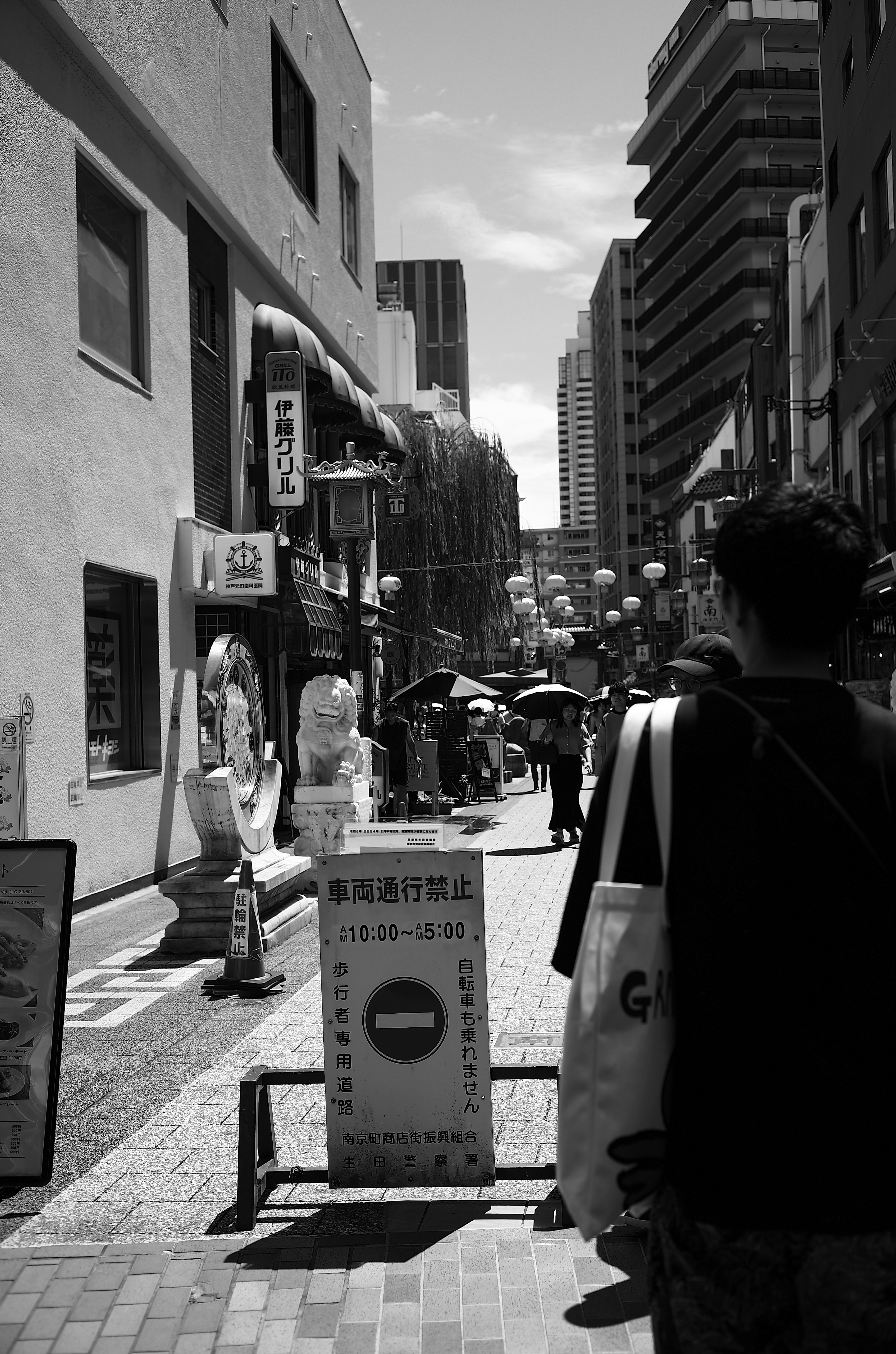 Black and white street scene with people walking and storefronts