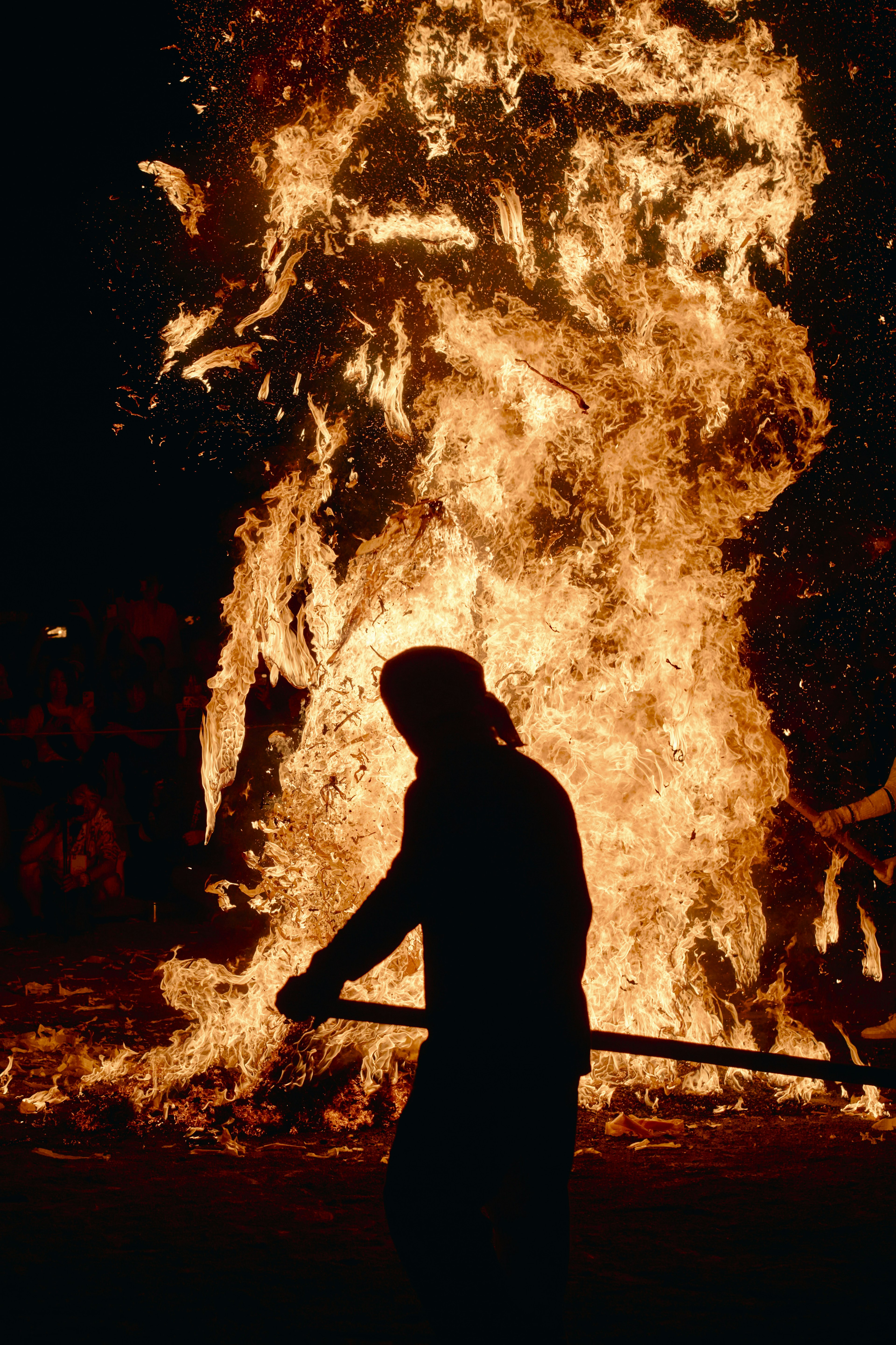 Silhouette of a person in front of a large fire during a festival