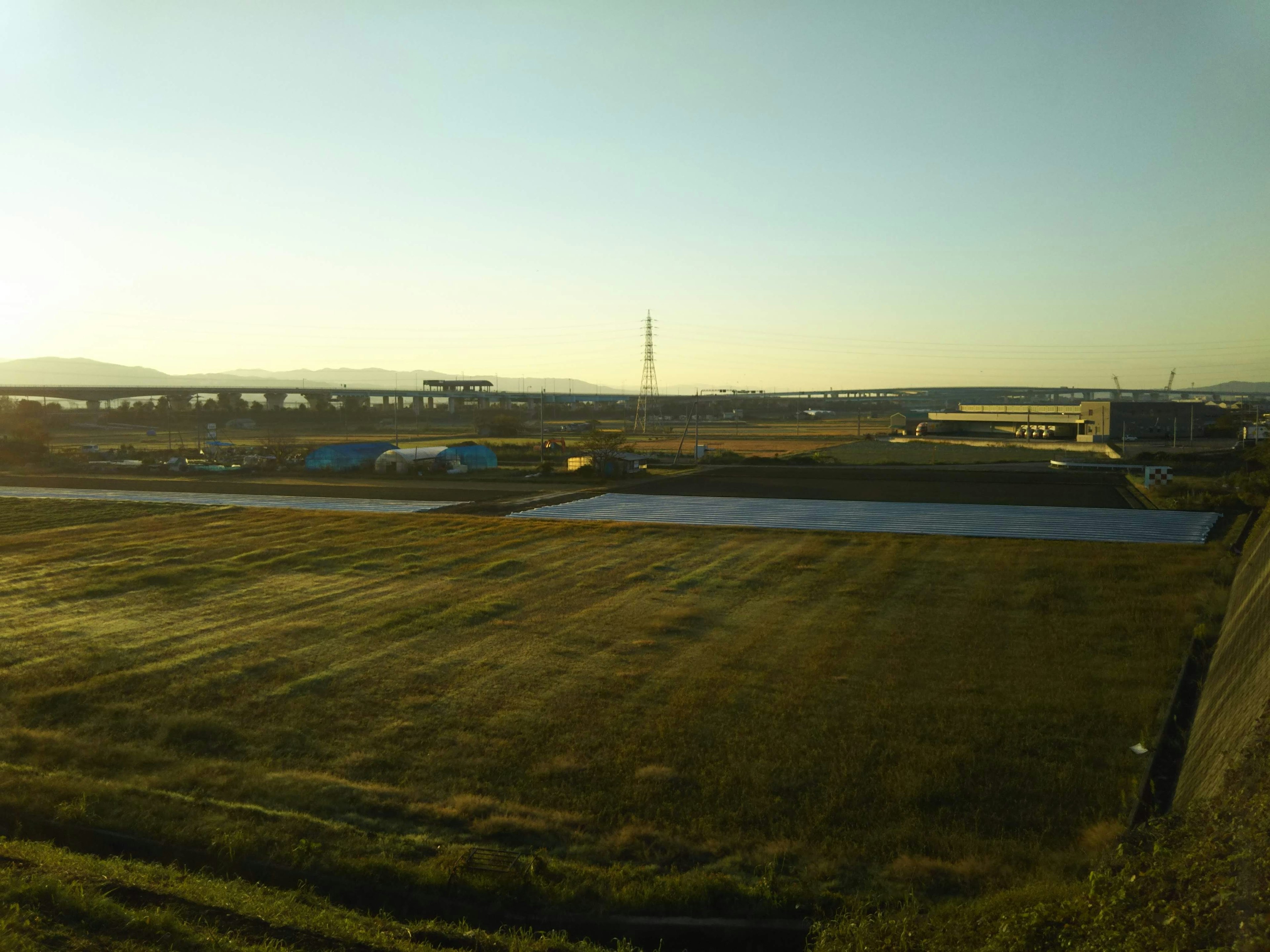 Expansive rural landscape under blue sky with industrial area