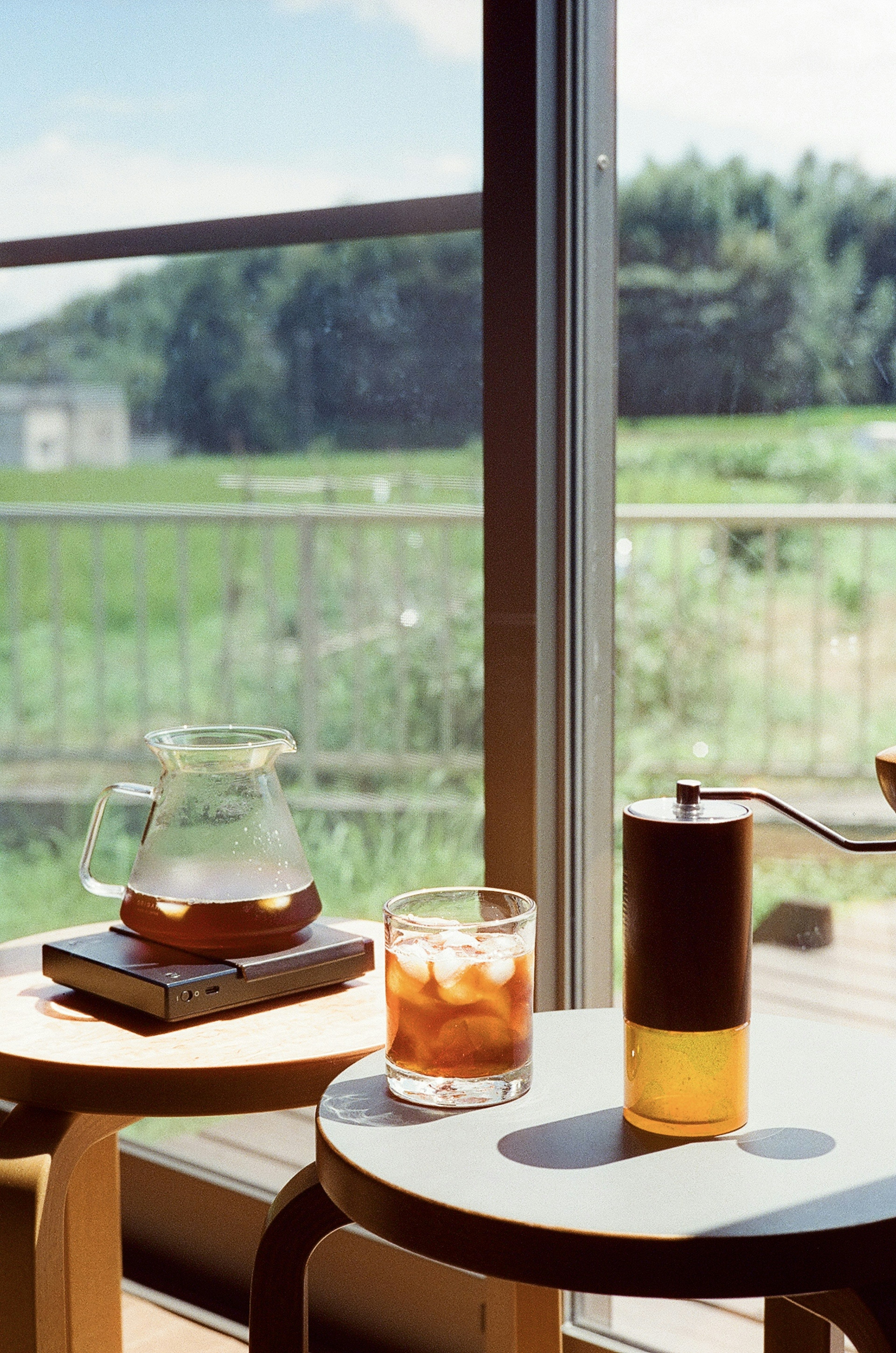 A serene view with a coffee setup and a glass of iced drink by the window