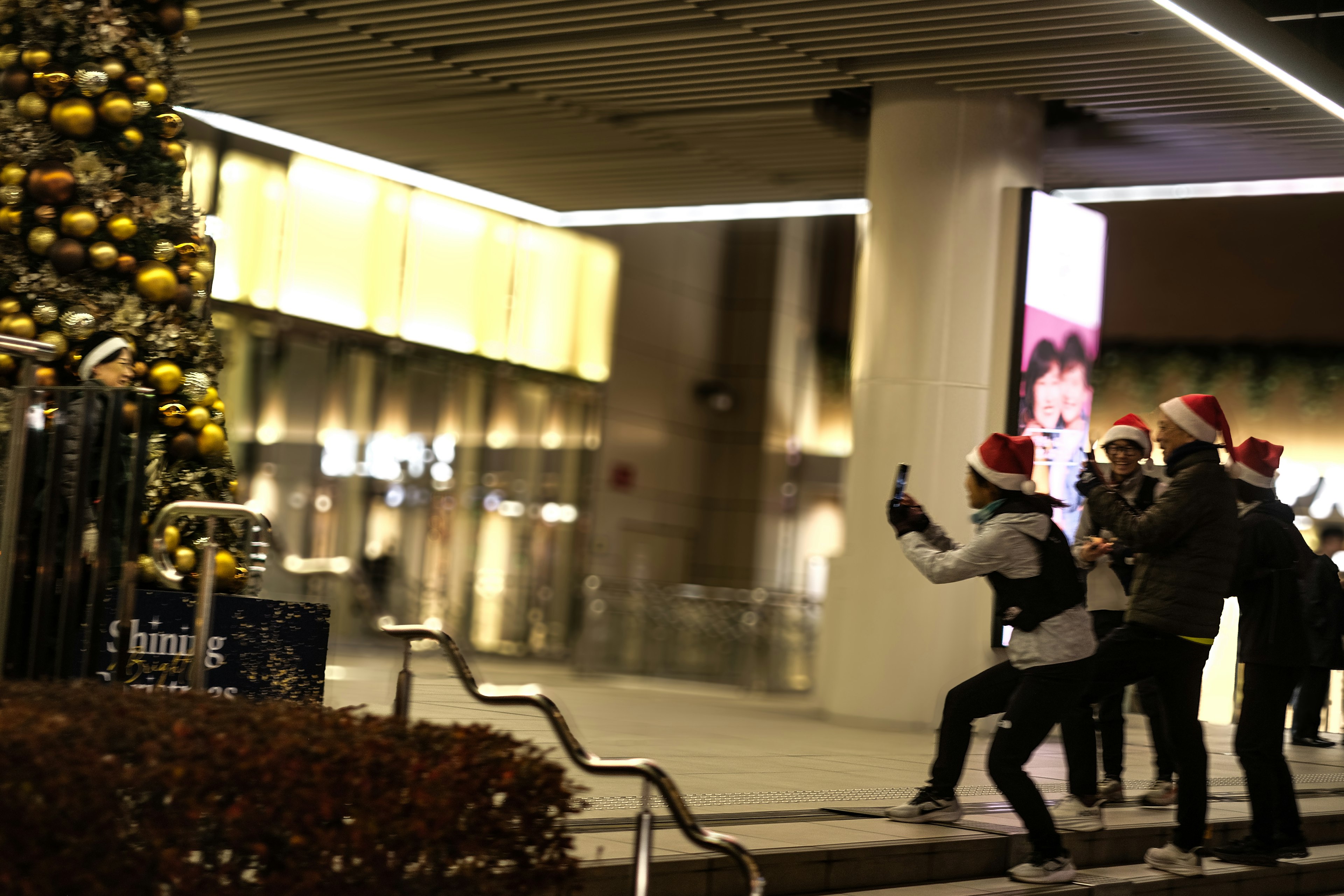 People wearing Christmas hats taking photos in front of a decorated tree