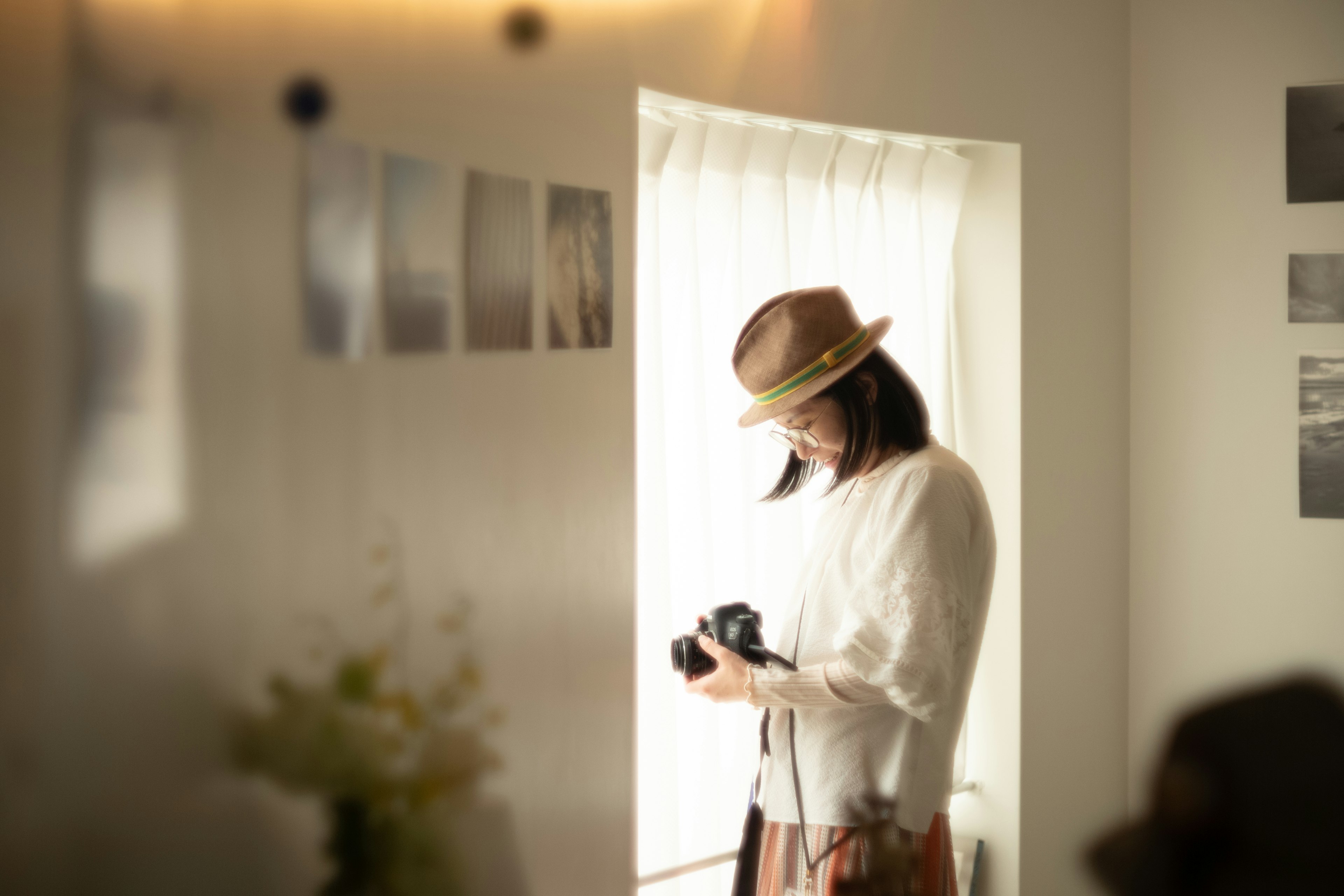 窓の近くでカメラを持つ女性が写っている部屋の中の風景