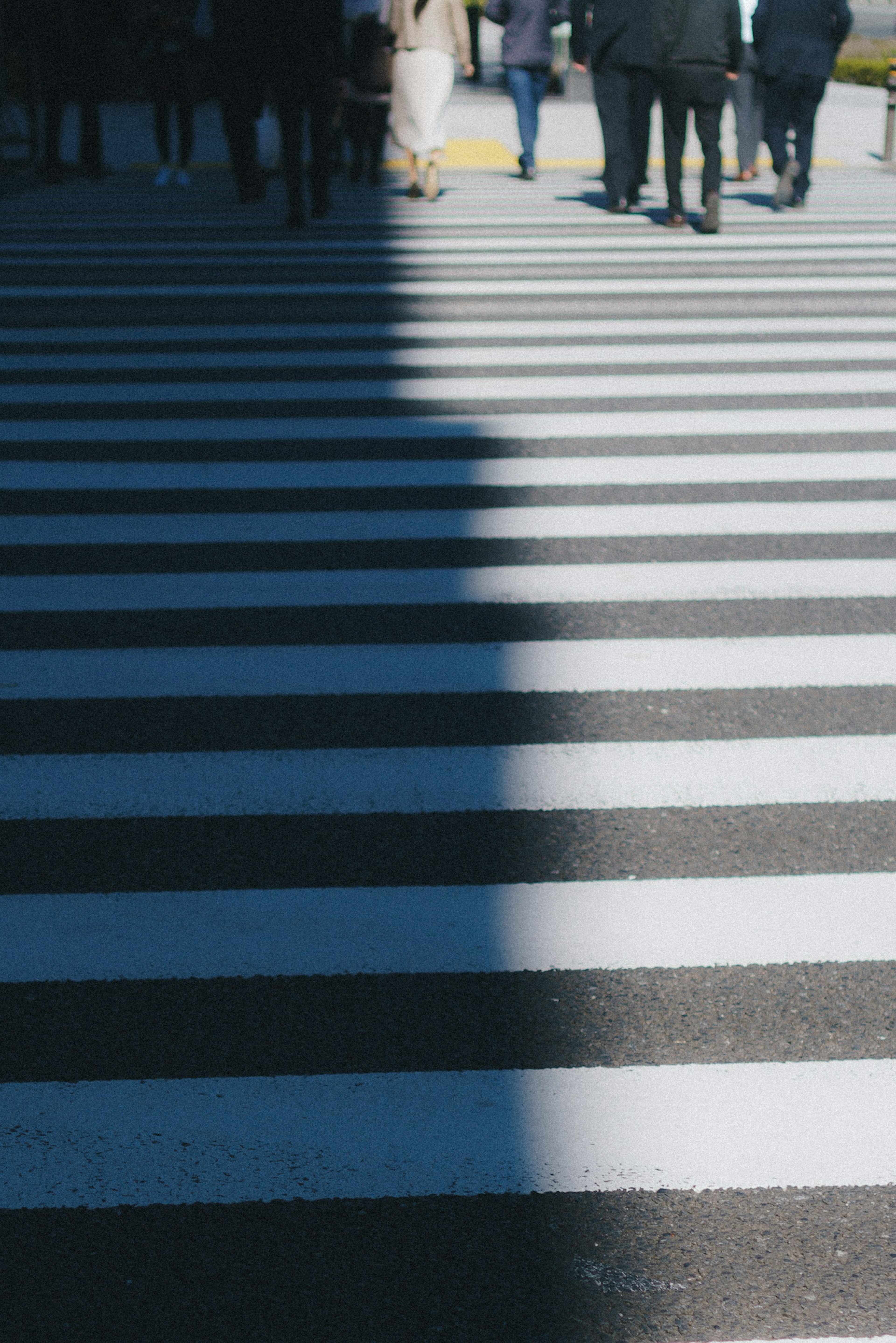 Paso de cebra con sombras y siluetas de peatones