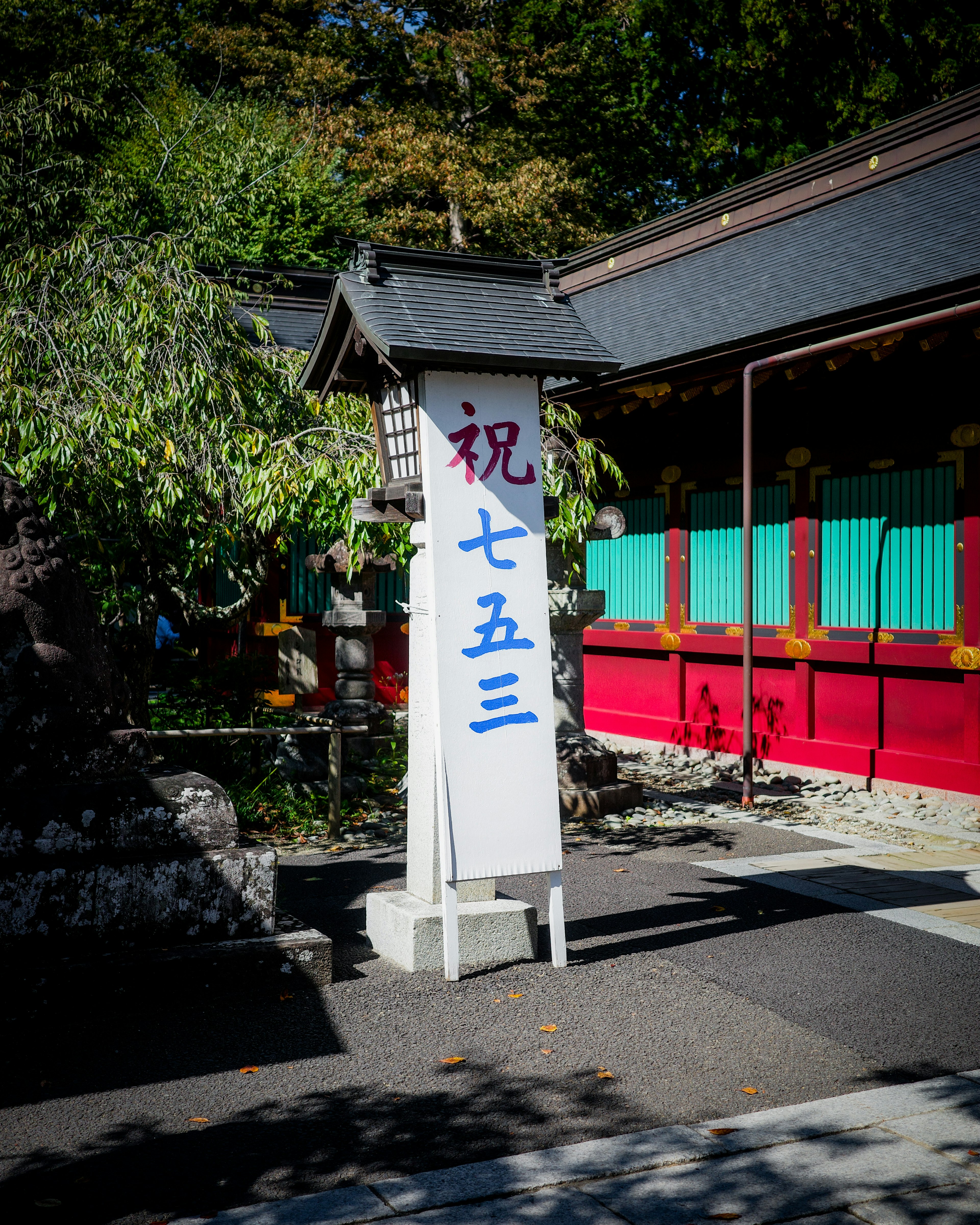 Signboard for Shichi-Go-San celebration in front of a colorful shrine