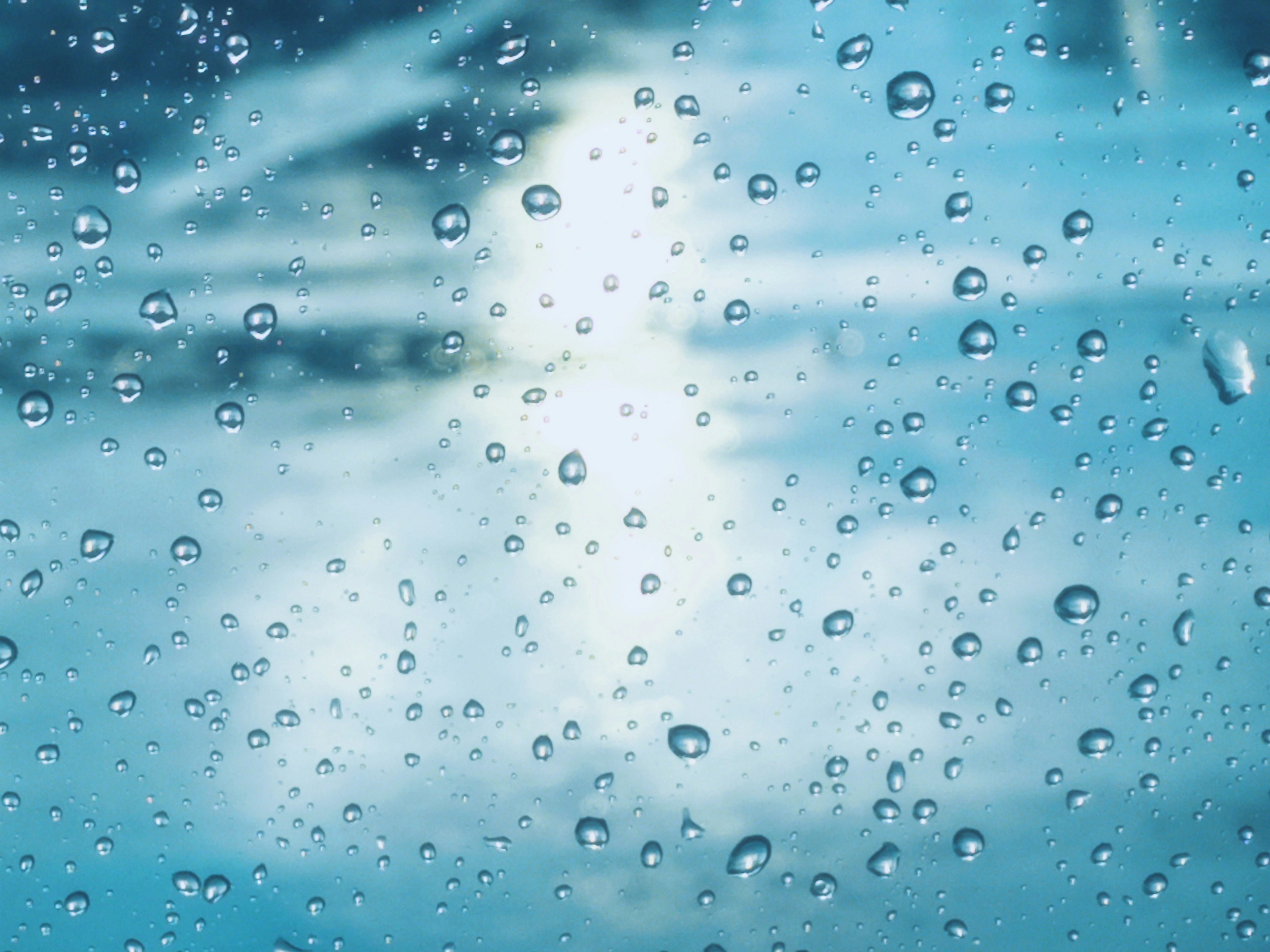 Immagine di gocce d'acqua su una finestra con uno sfondo di cielo blu