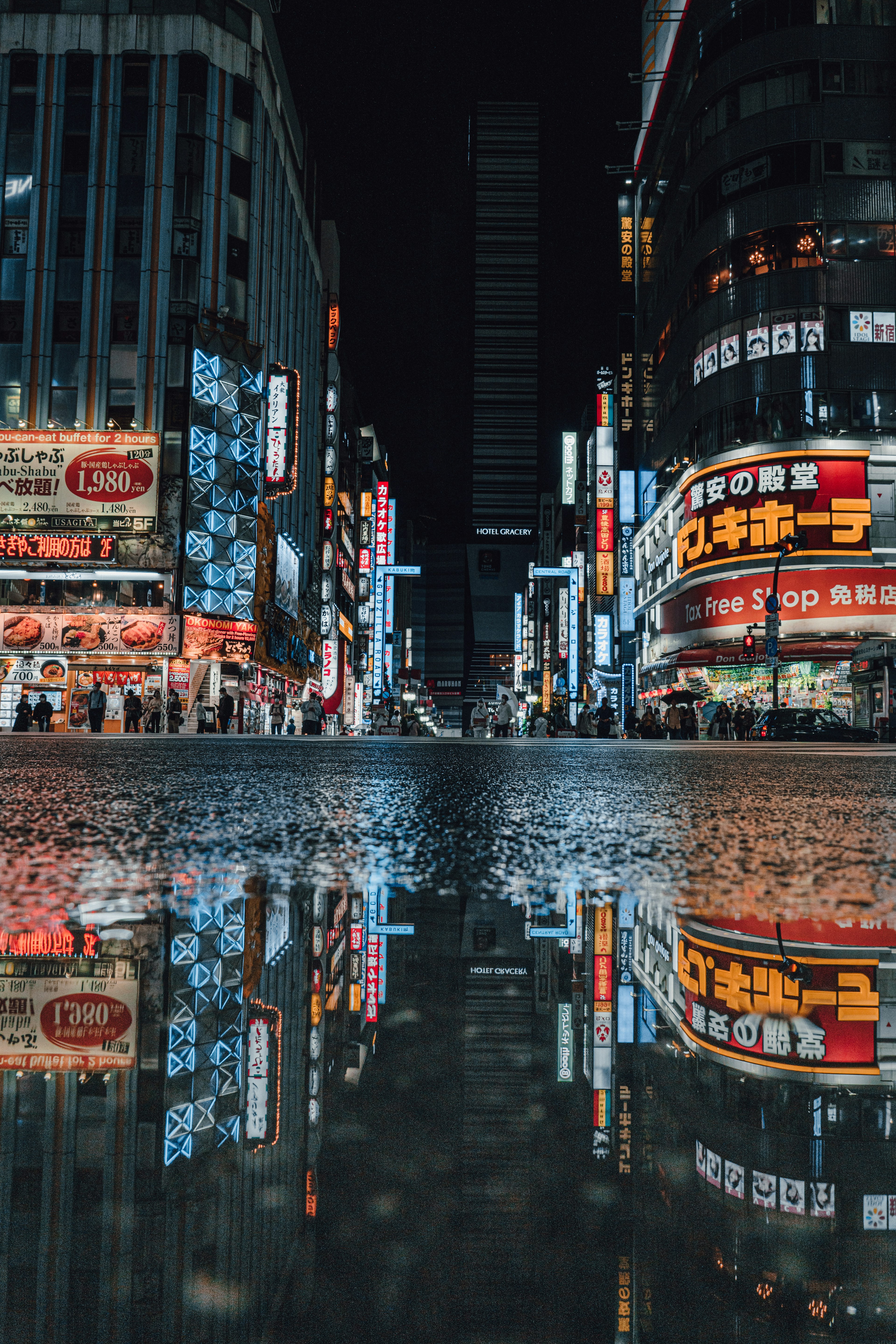 夜の街並みと水たまりの反射が美しい都市の風景