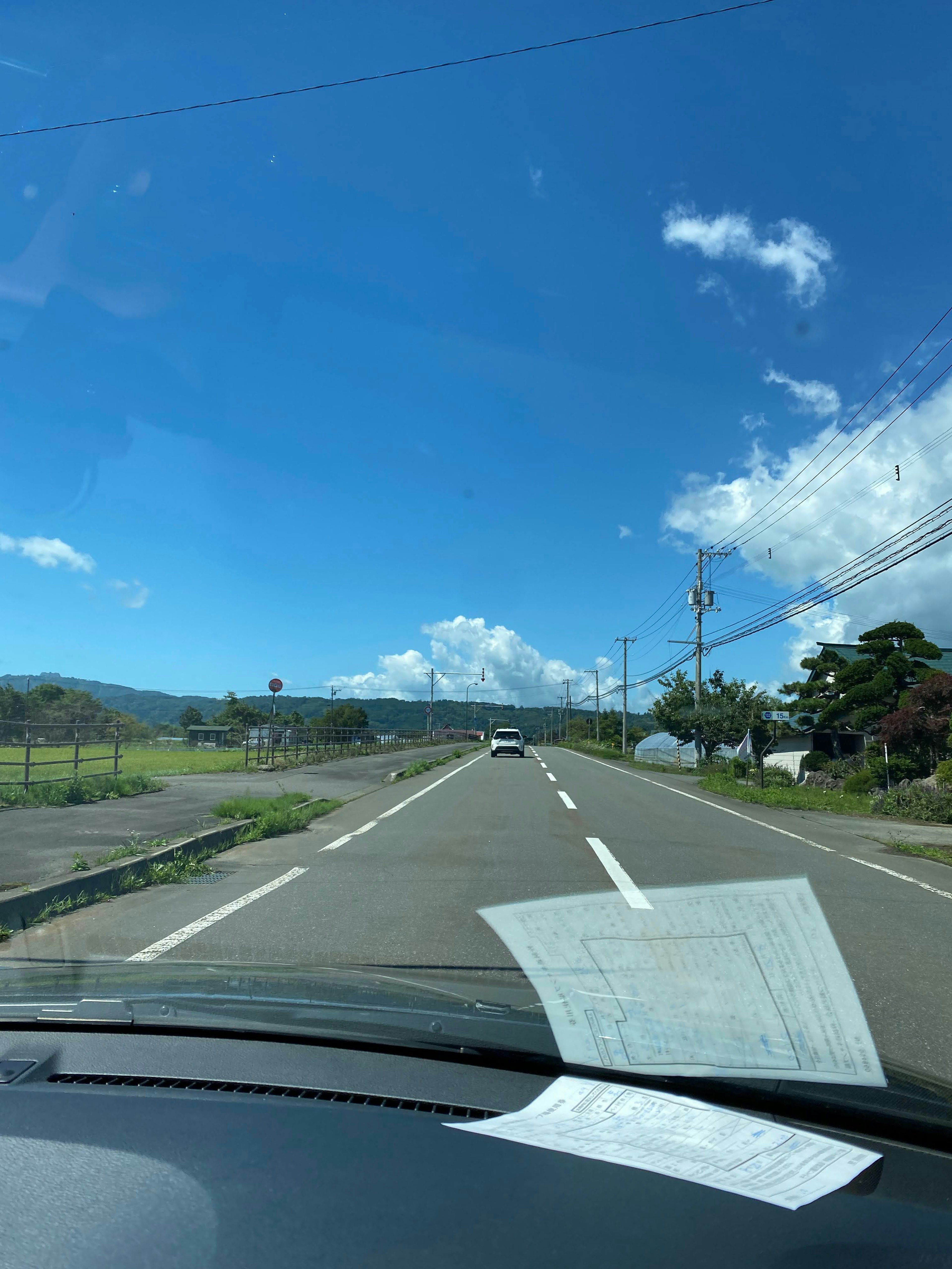 青空と白い雲が広がる田舎道の風景