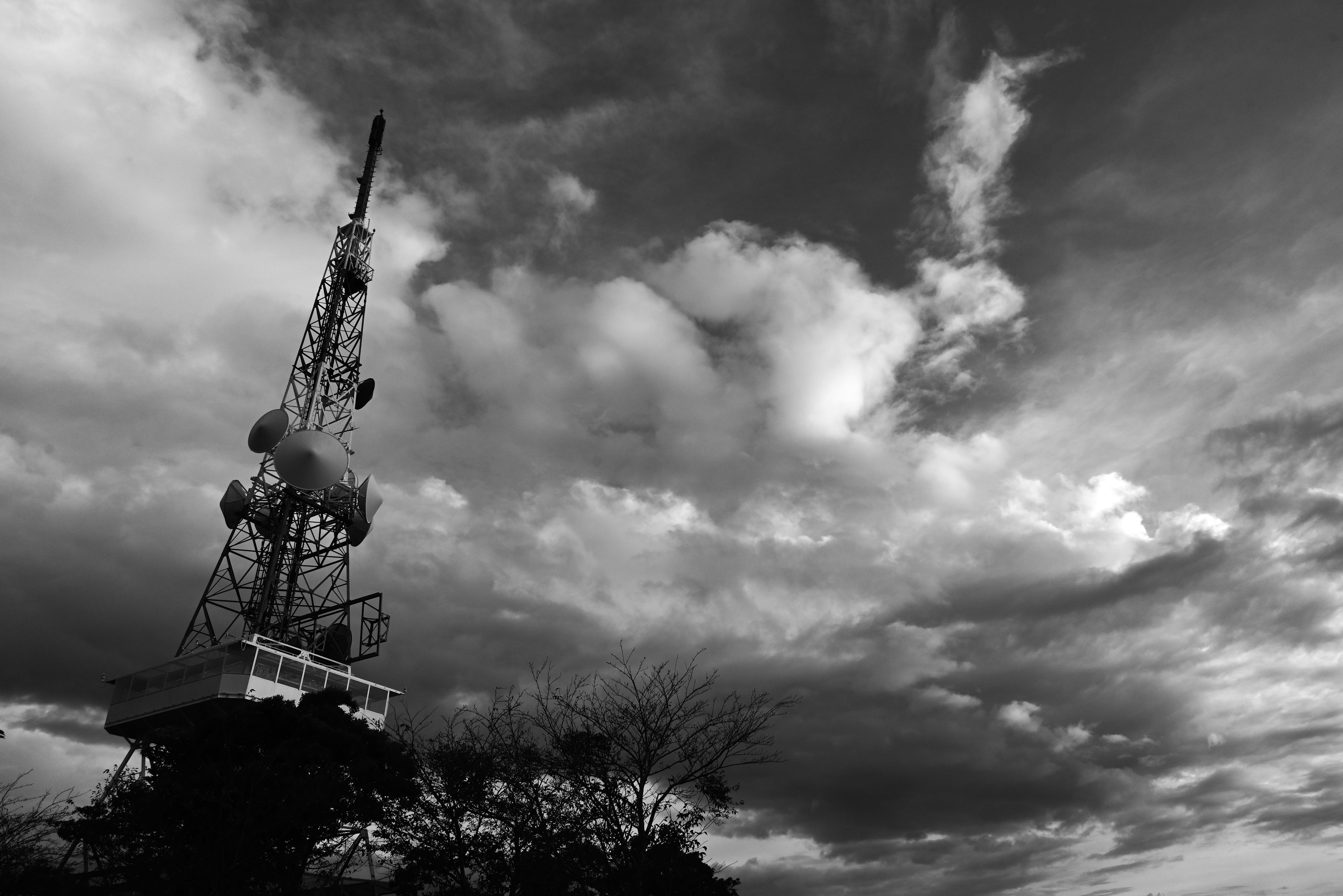 Siluet menara komunikasi di latar belakang langit hitam putih yang dramatis