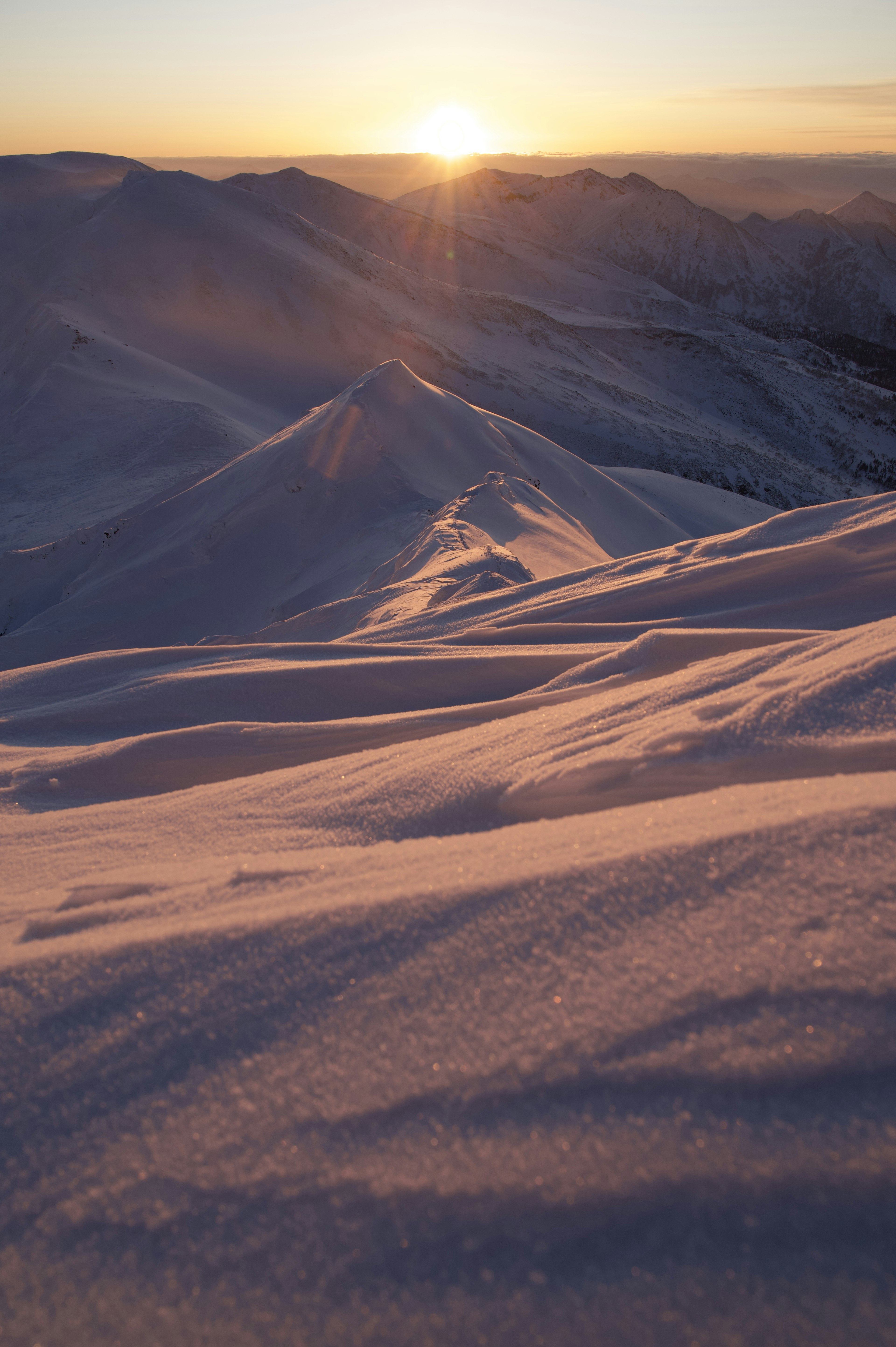 Montagne innevate con un sole che sorge