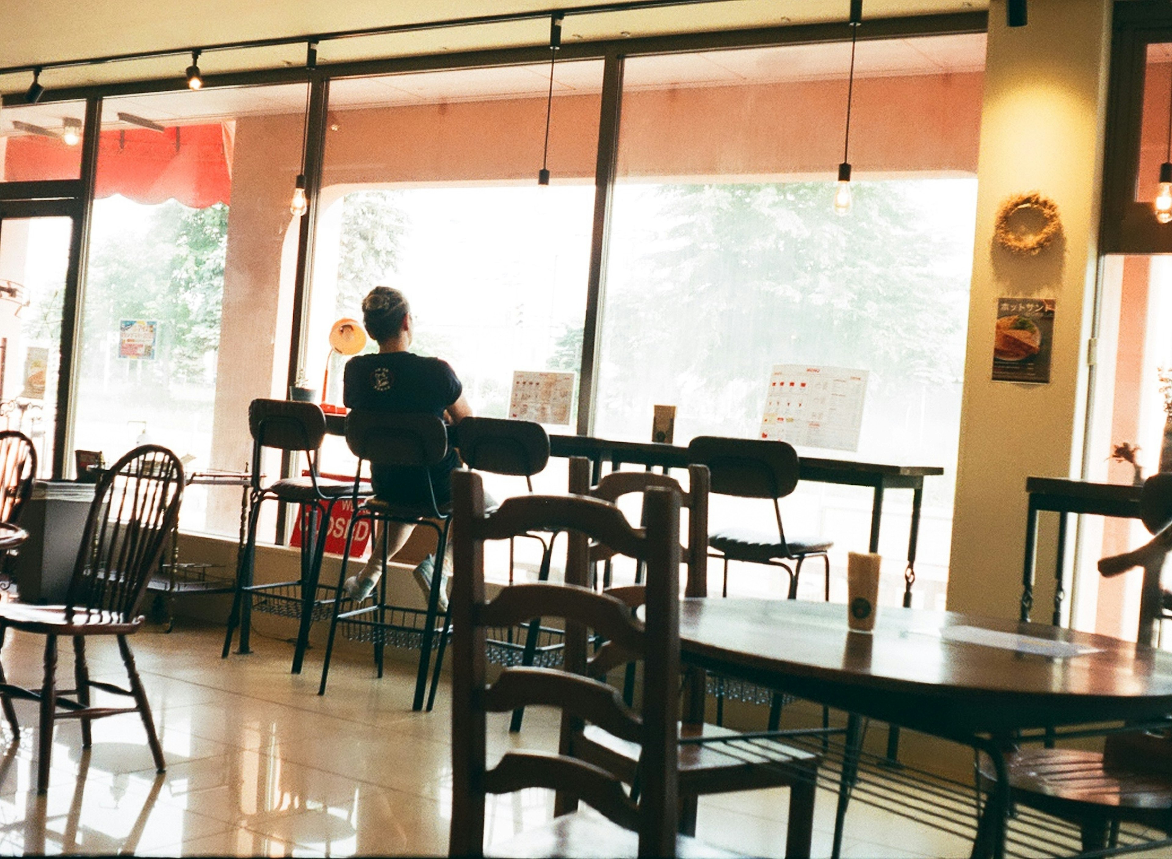 カフェの内部で窓際に座る人物とテーブルの風景