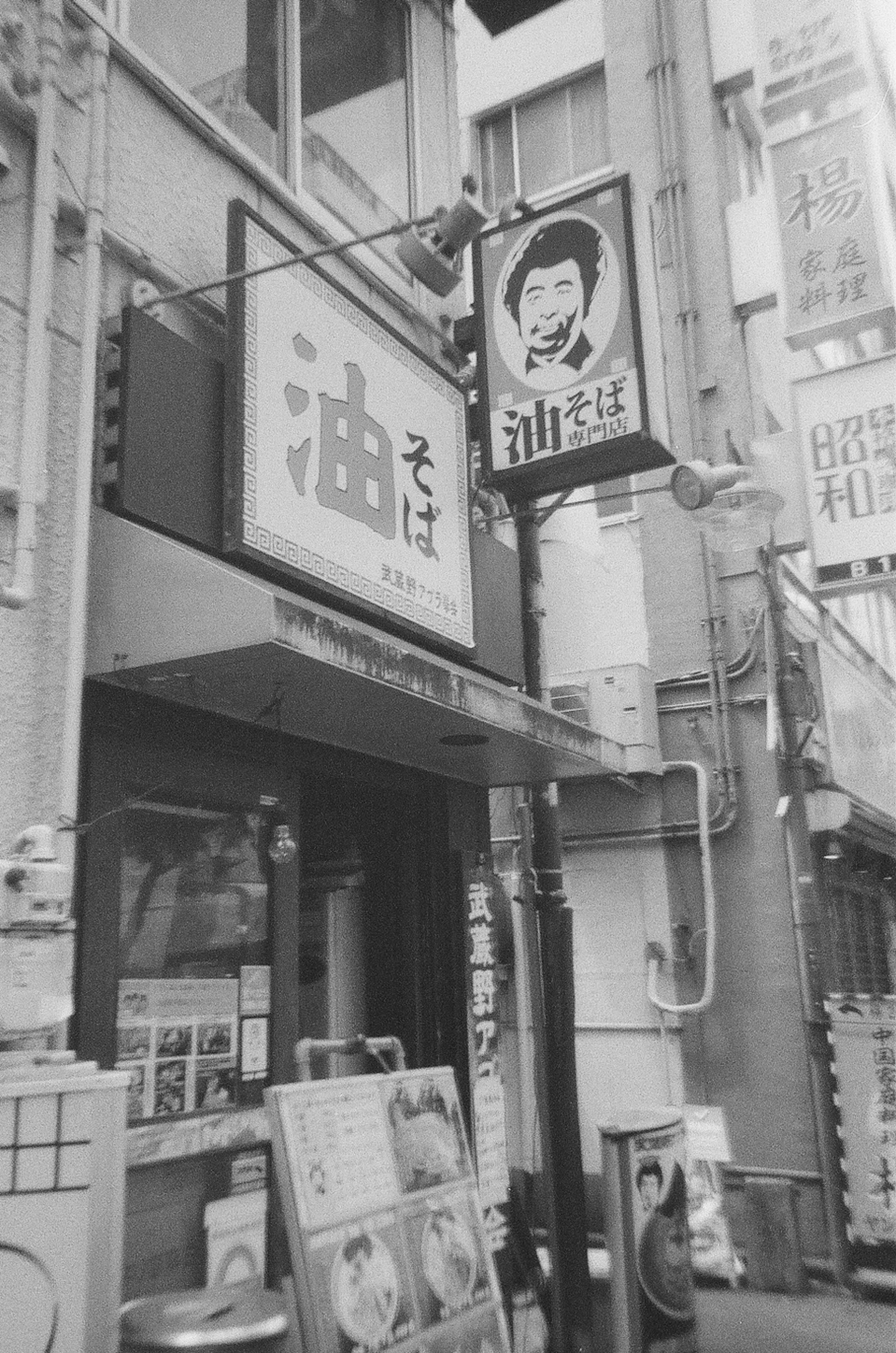 Exterior of a Japanese soba restaurant in black and white with prominent signs and menus