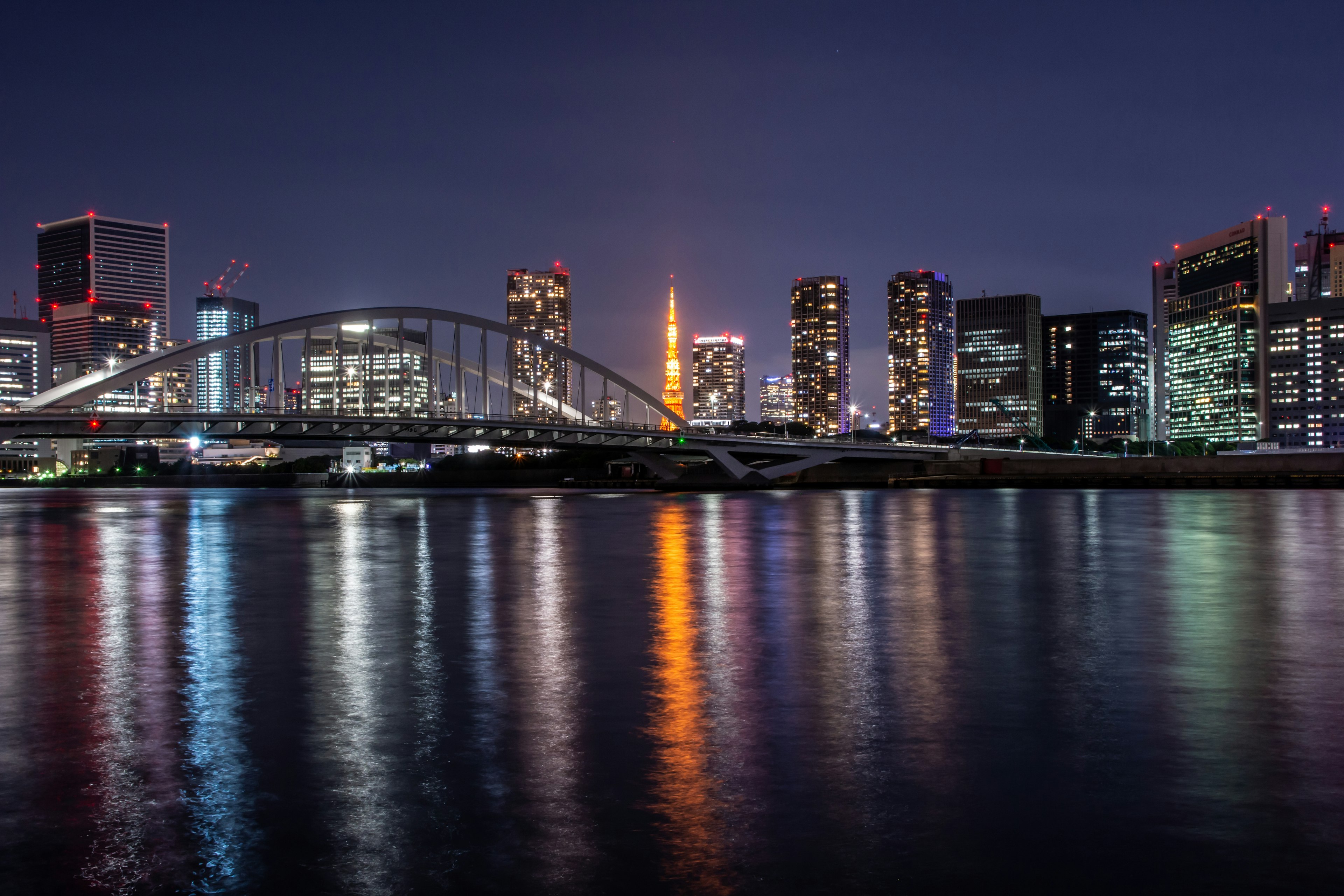 Vista notturna dello skyline di Tokyo con la Torre di Tokyo che si riflette nel fiume