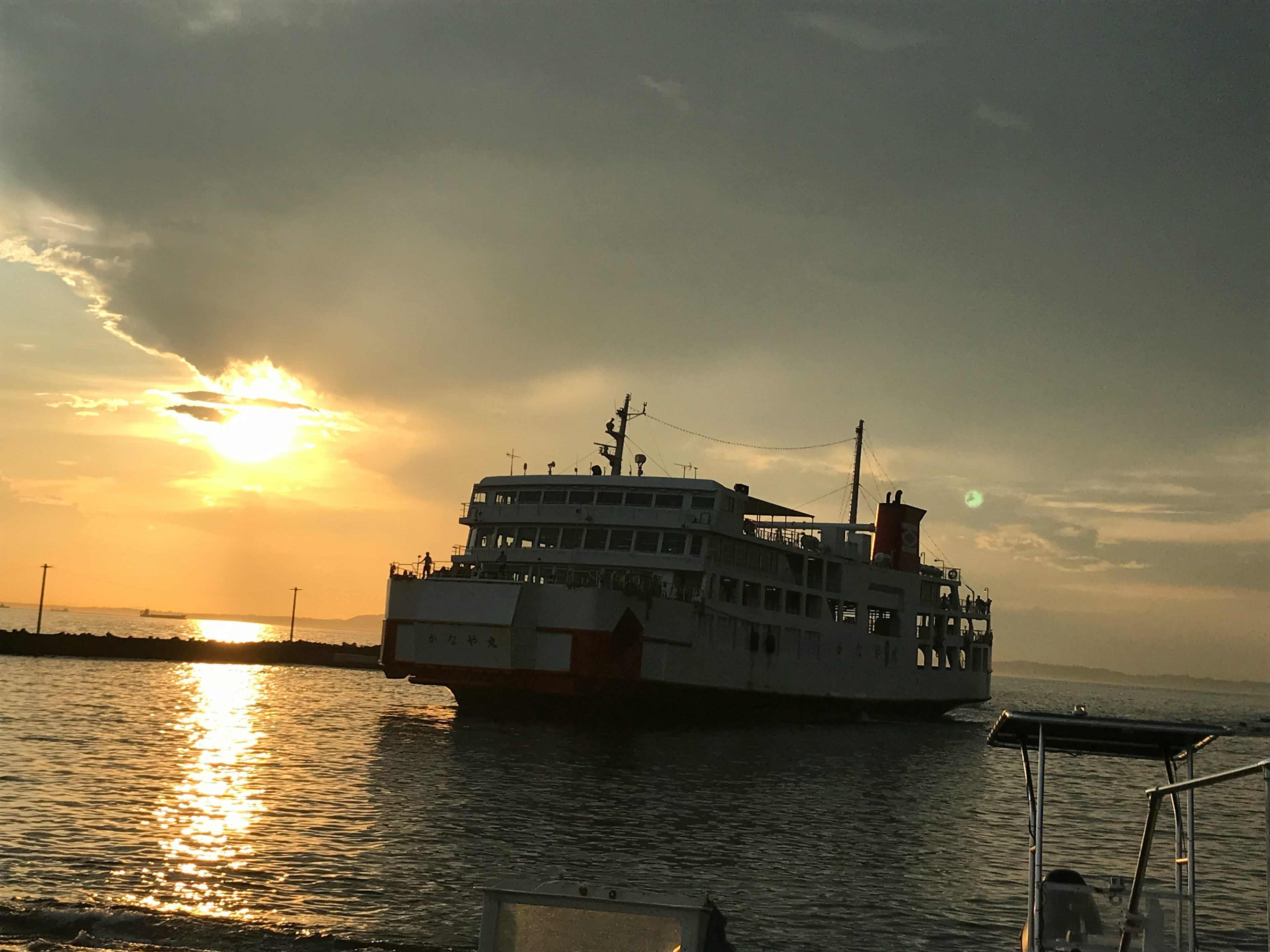 A ferry silhouetted against a sunset with reflections on the water