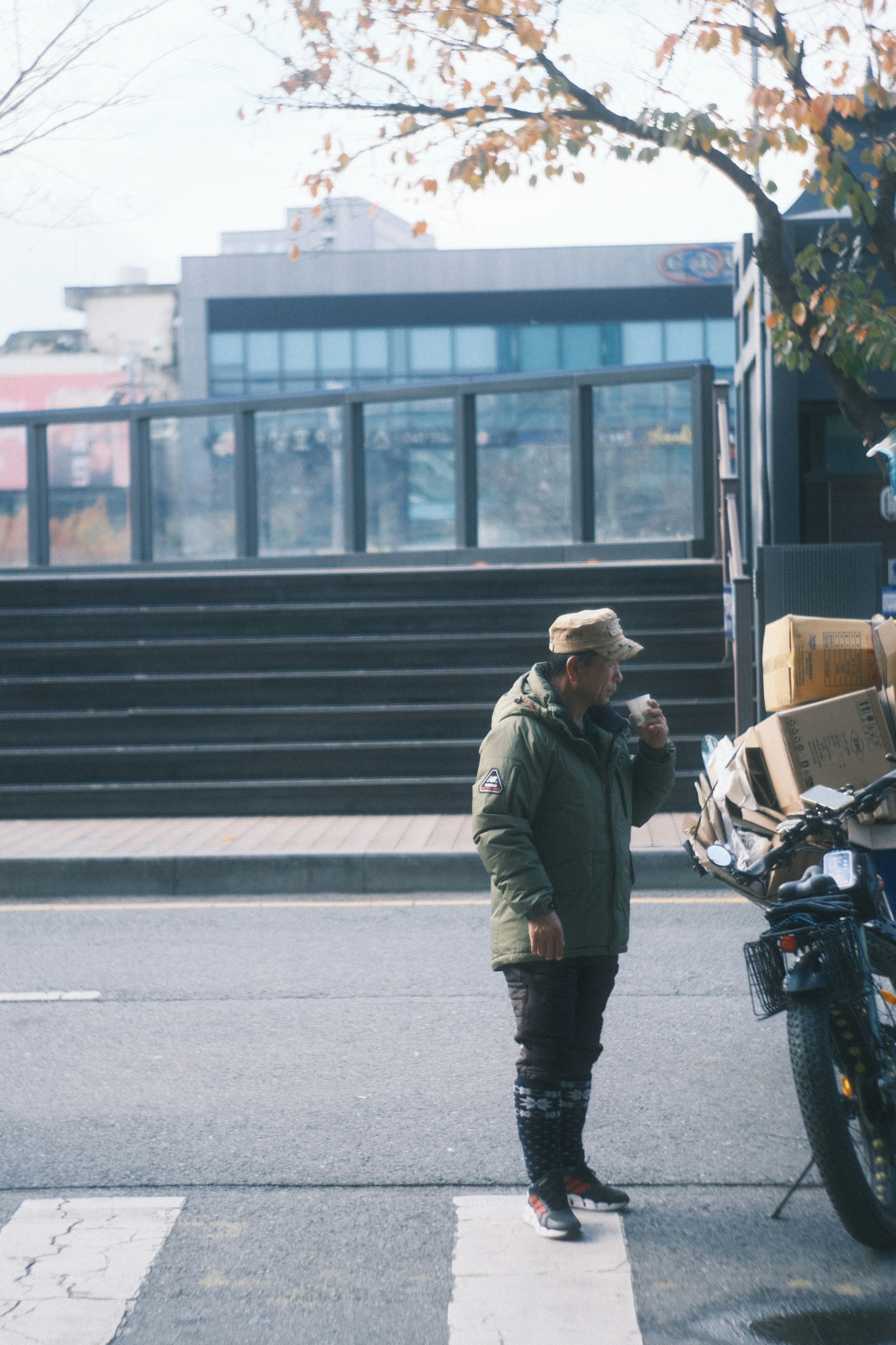 街で飲み物を飲む男性とバイクの近くに立っている様子