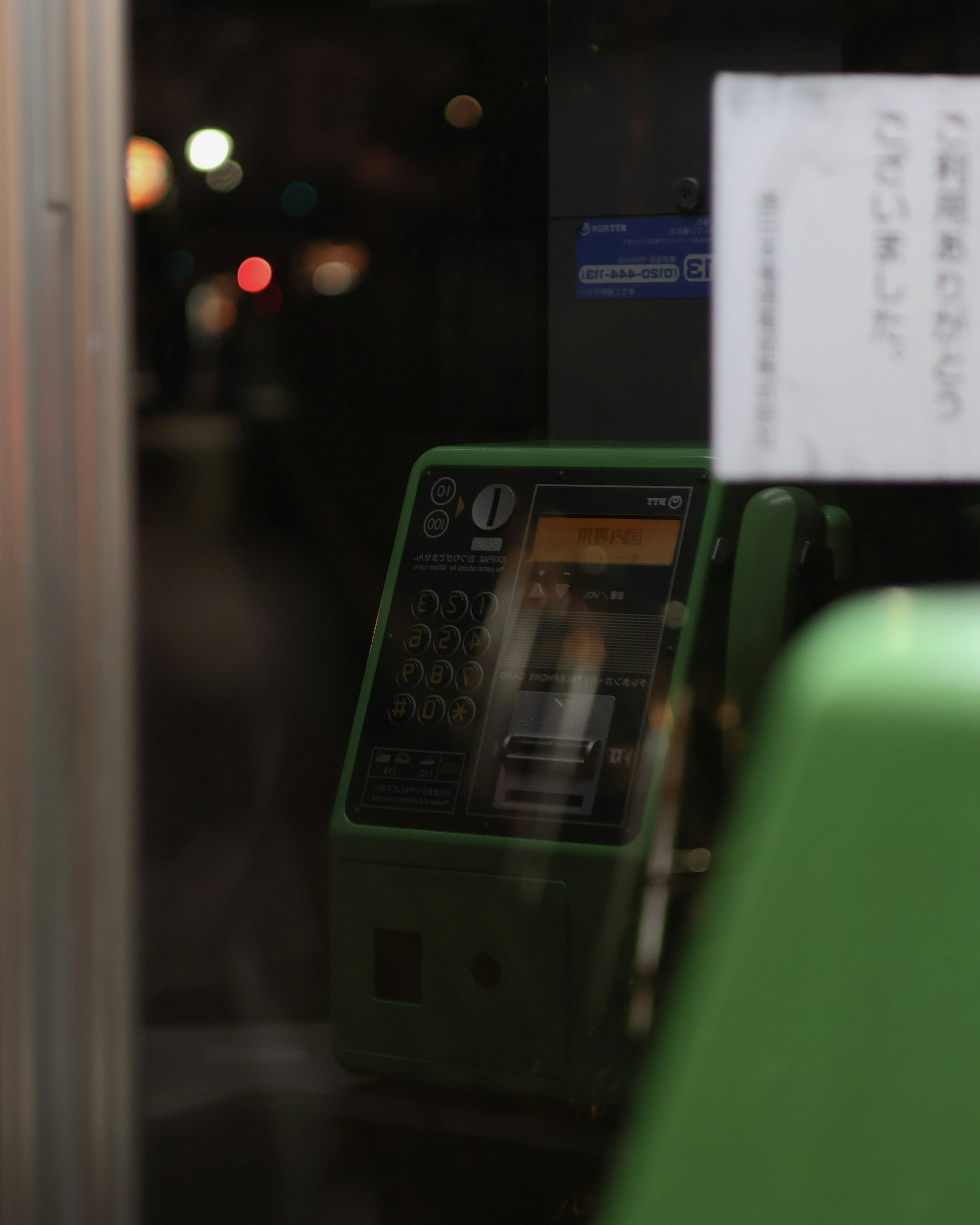 Ein grüner Fahrkartenautomat vor einem dunklen Hintergrund sichtbar