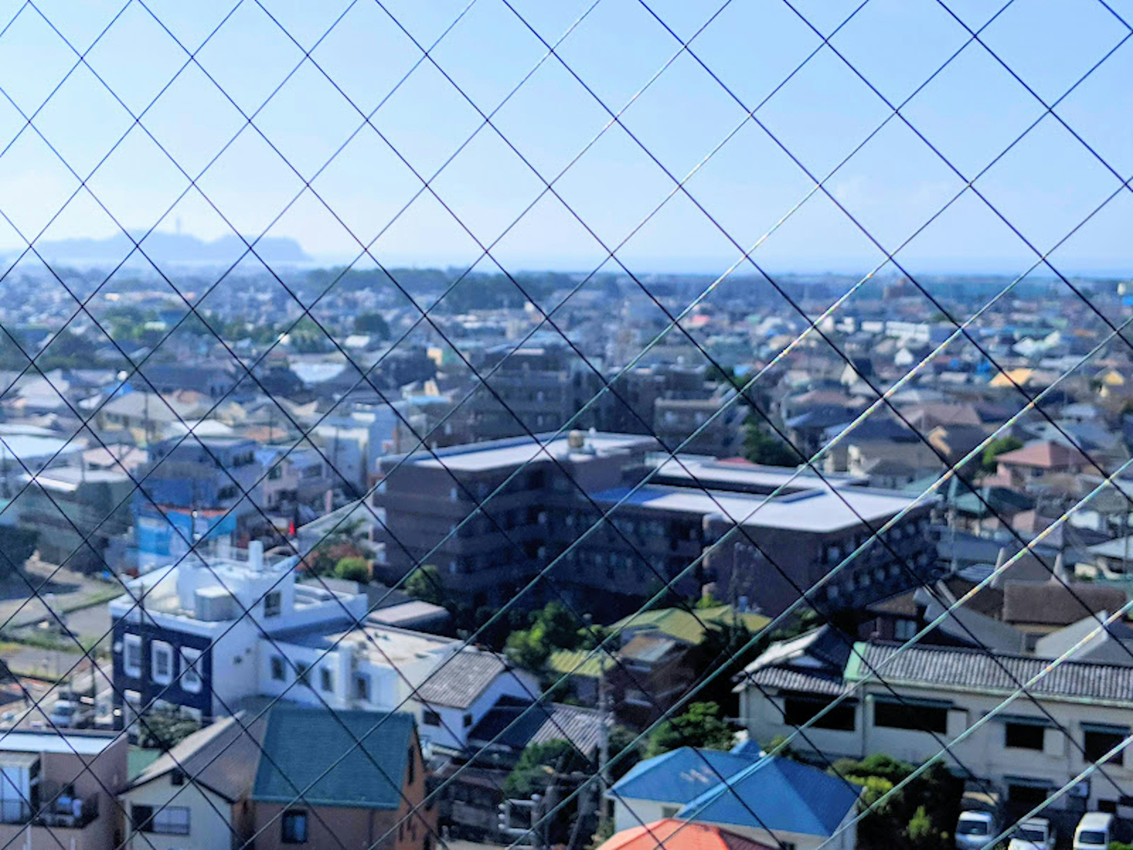 Vista di un'area residenziale sotto un cielo blu vista attraverso una finestra a griglia