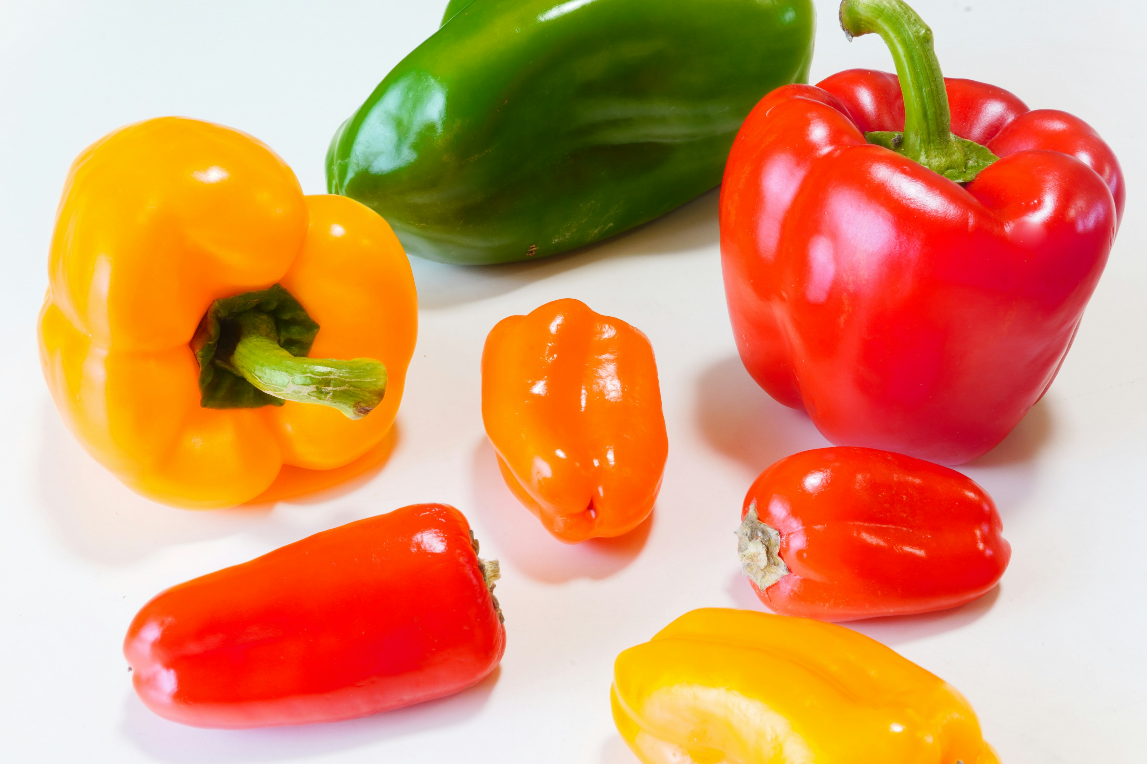 A variety of colorful bell peppers arranged on a white surface