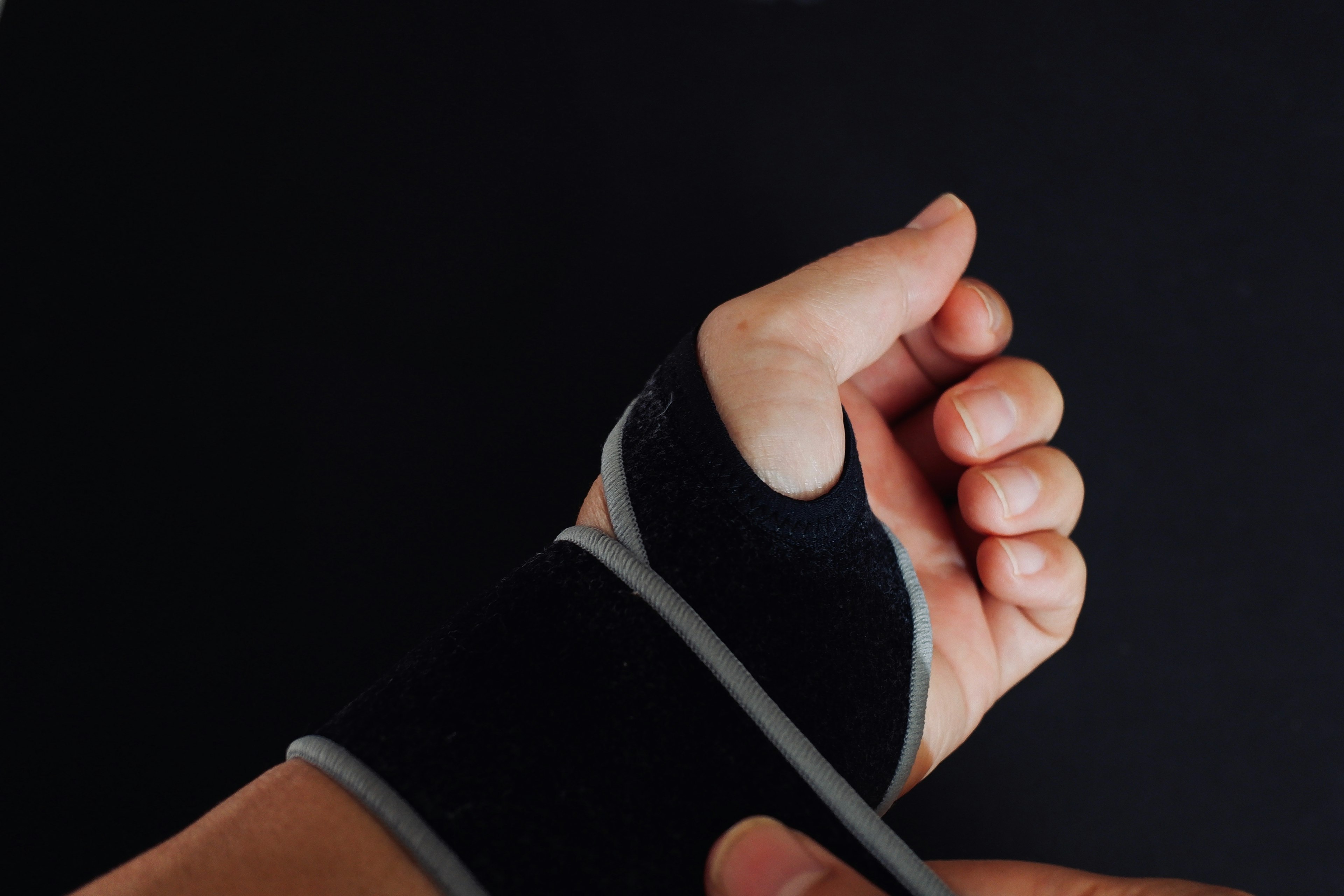 Hand wearing a wrist support on a black background