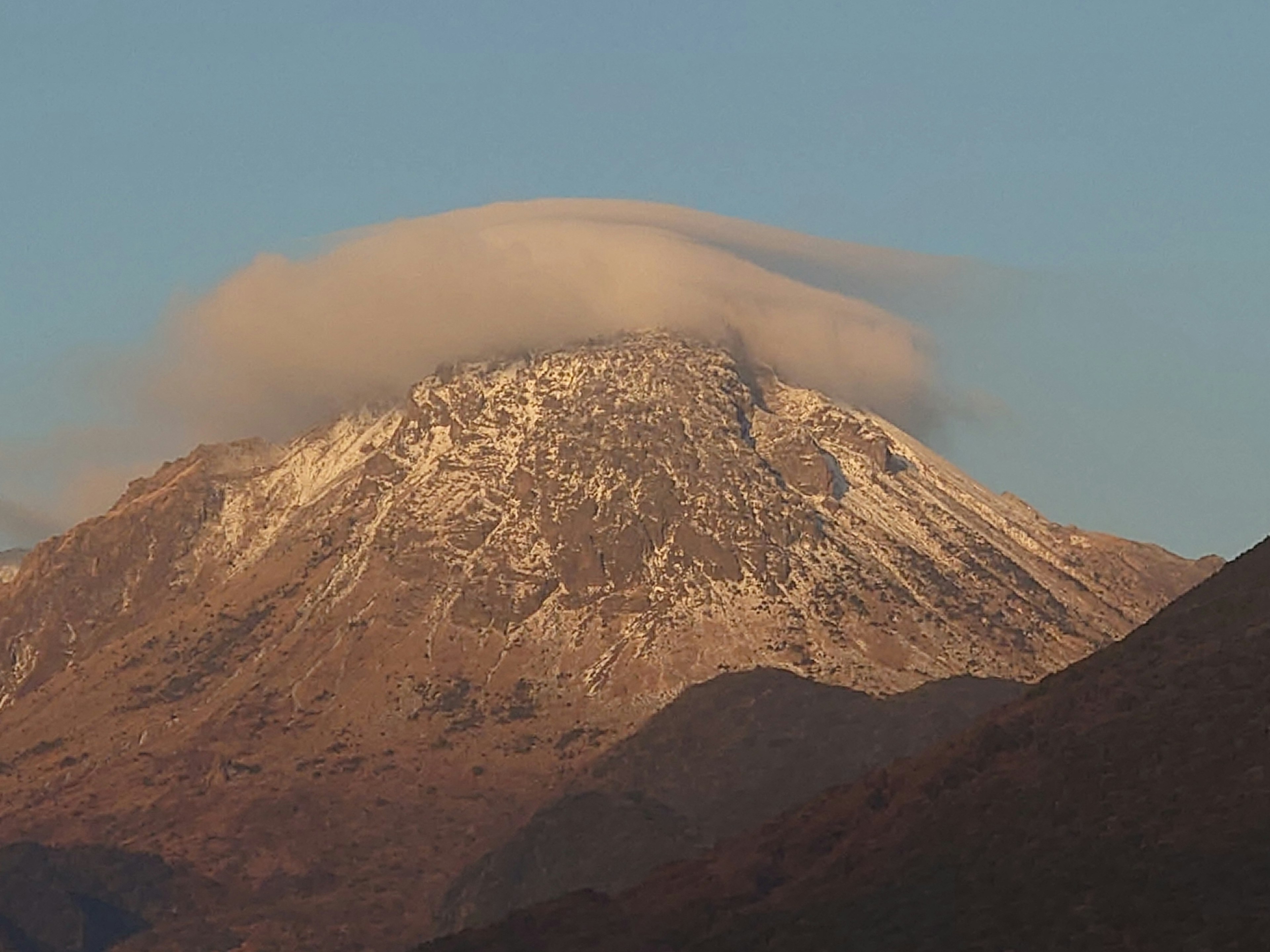 雪を頂いた山の頂上に雲がかかる風景